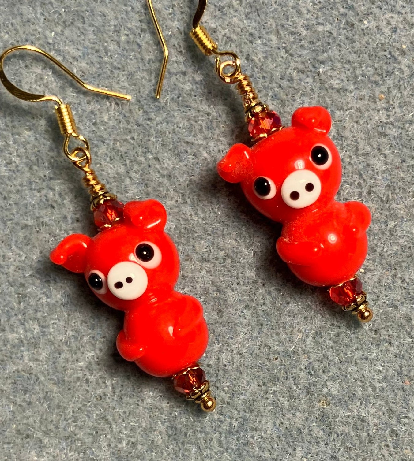 Red lamp work standing pig bead earrings adorned with red Chinese crystal beads.