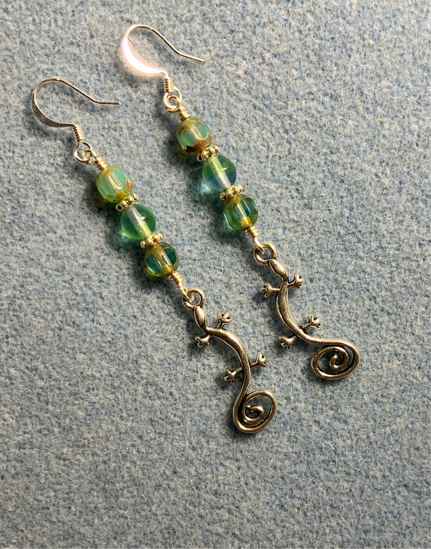 Long silver swirly tailed lizard charm earrings adorned with light green Czech glass beads