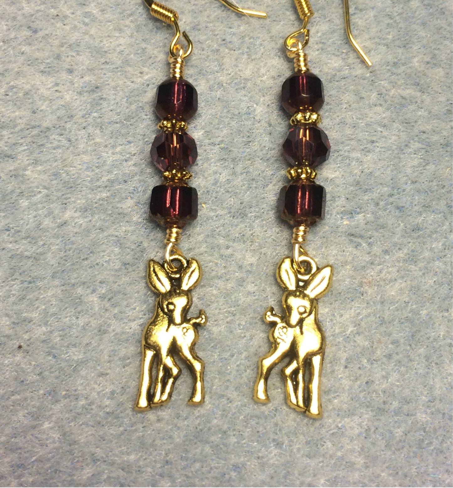 Gold deer charm earrings adorned with purple Czech glass beads.
