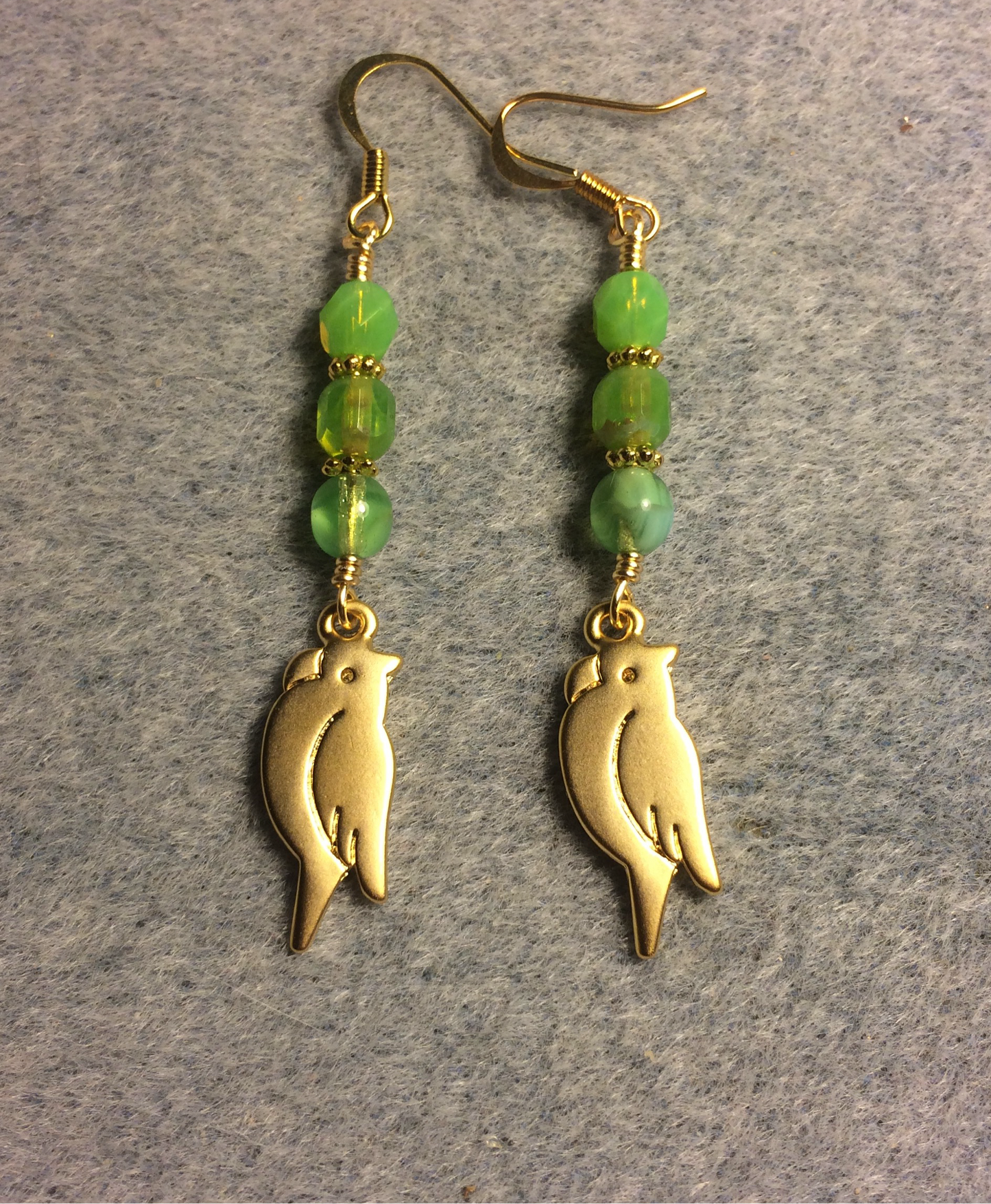 Gold parrot charm earrings adorned with lime green Czech glass beads