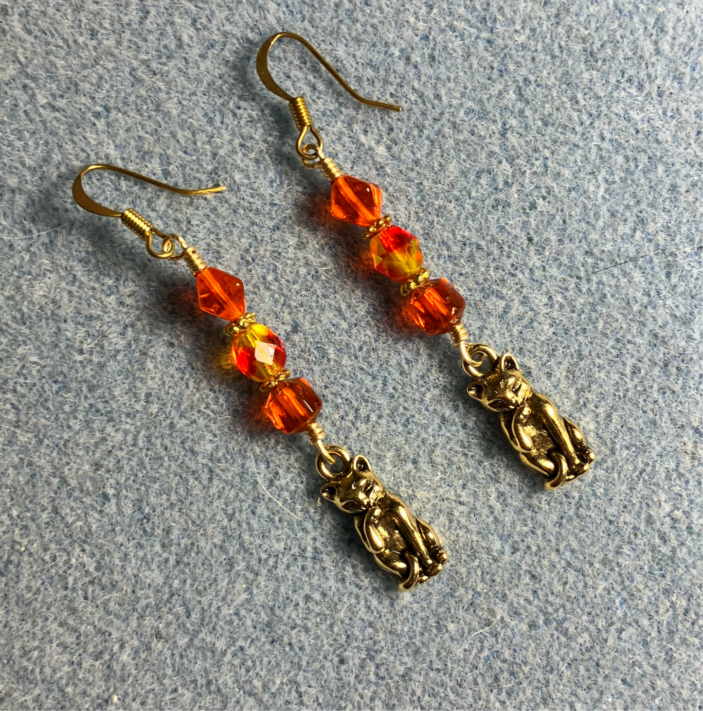Gold cat charm earrings adorned with orange Czech glass beads
