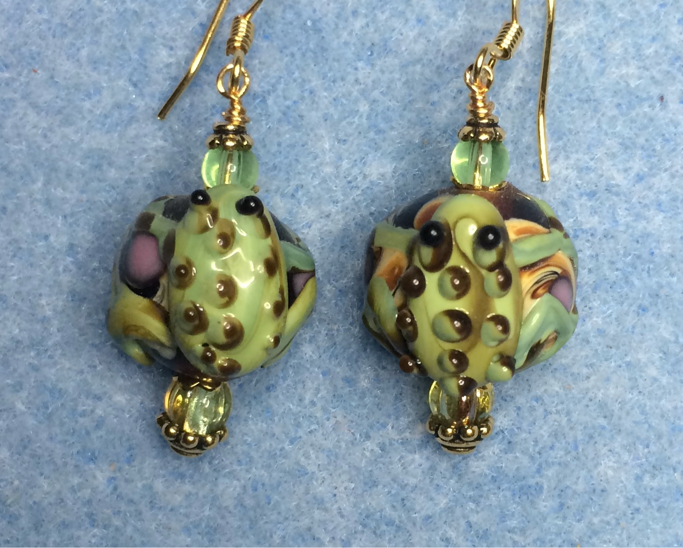 Brown and green lamp work frog bead earrings adorned with green Czech glass beads.