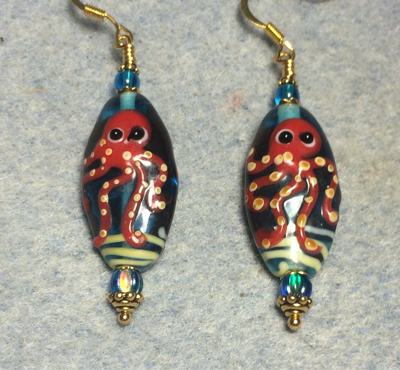 Turquoise and dark red lamp work octopus bead earrings adorned with turquoise Czech glass beads.