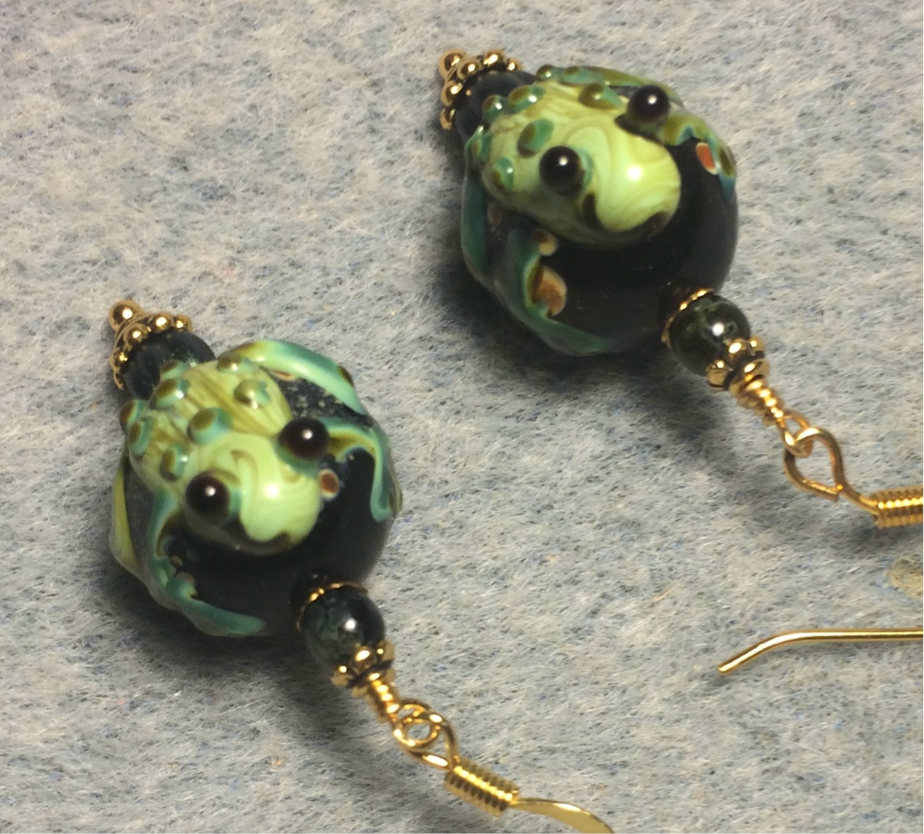 Black and dark green lamp work frog bead earrings adorned with dark green Czech glass beads.