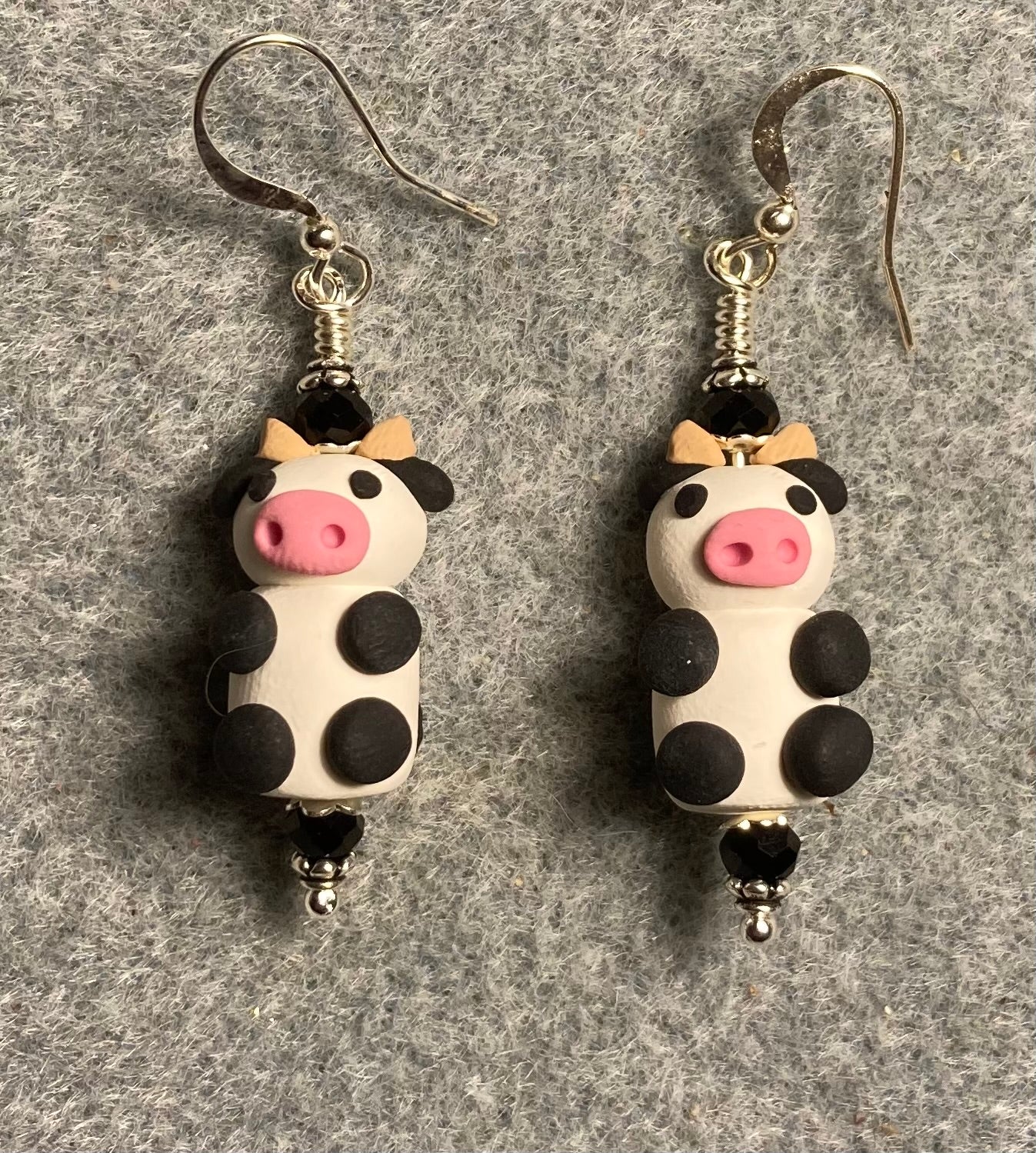 Small black, white and pink polymer clay cow bead earrings adorned with black Chinese crystal beads.