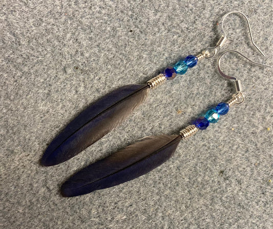 Small rare iridescent blue Pionus parrot feather earrings adorned with small dark blue and turquoise Chinese crystal beads.