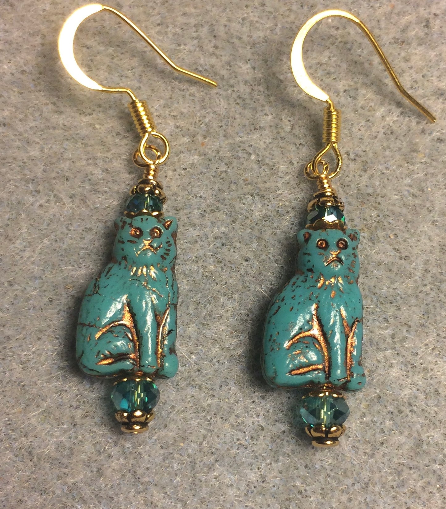 Small dark turquoise (with gold inlay) Czech glass cat bead earrings adorned with dark turquoise Chinese crystal beads.