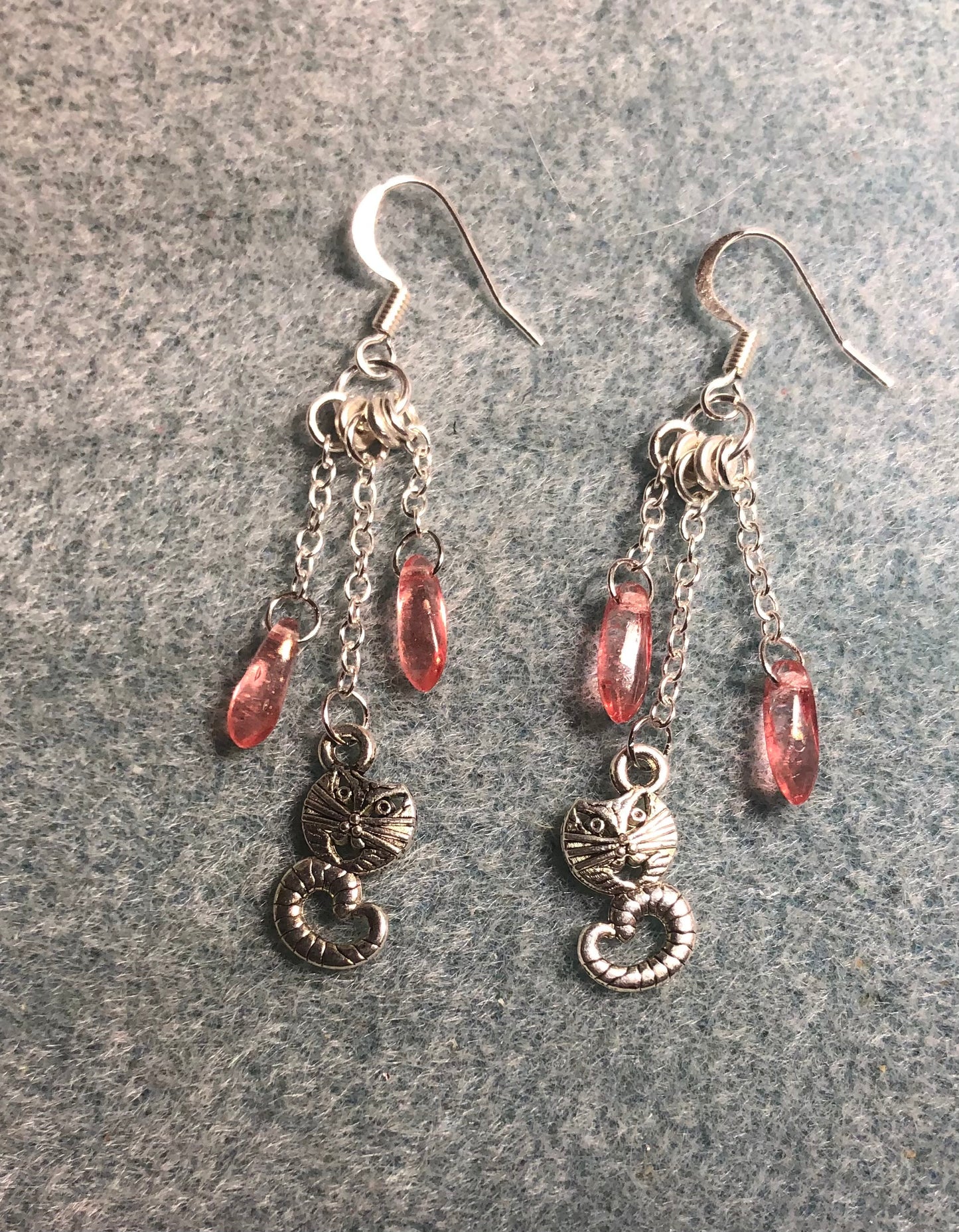 Small silver Cheshire cat charm earrings attached to silver chain and adorned with small pink Czech glass dagger beads
