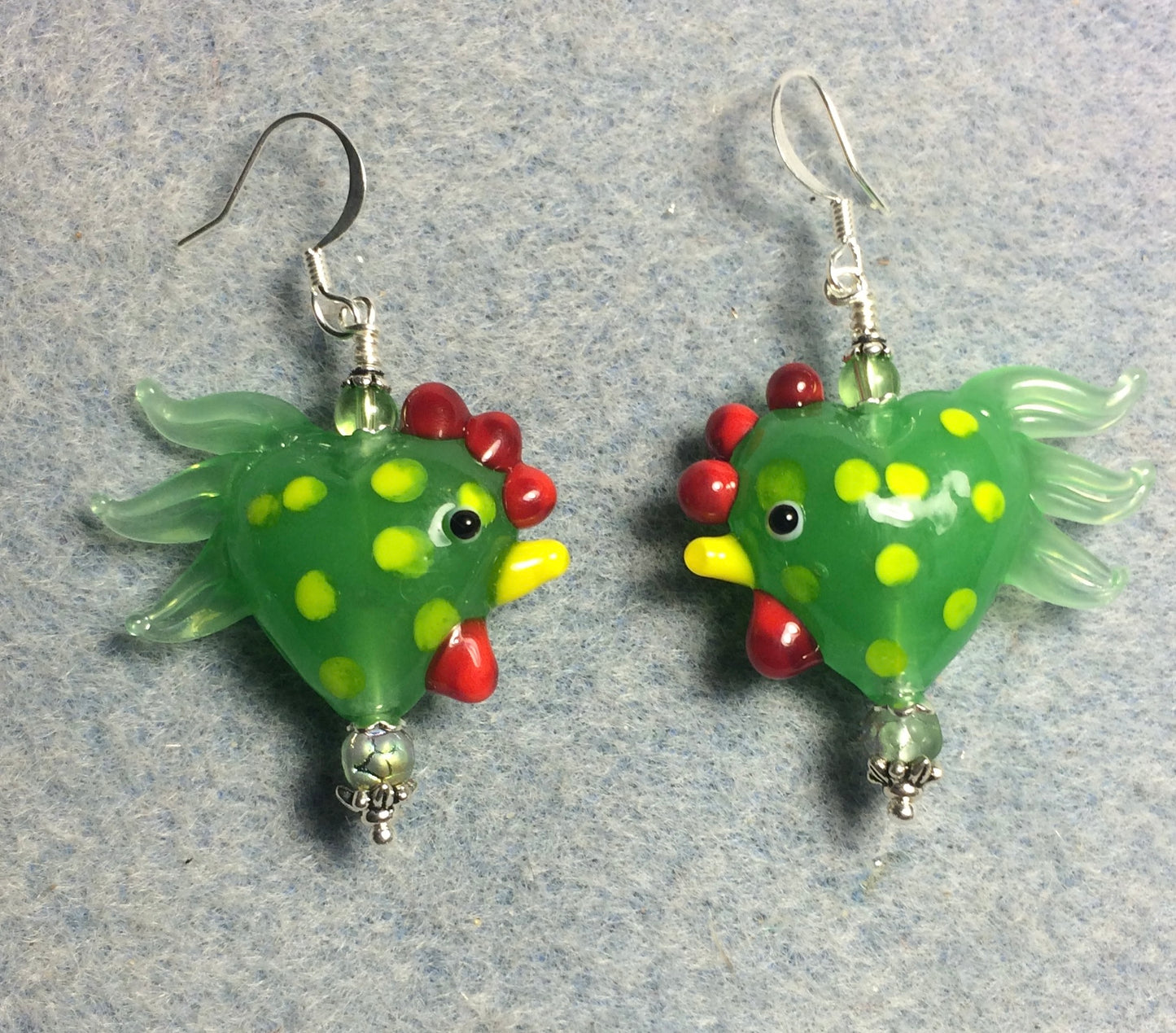 Green with yellow spots heart shaped lamp work rooster bead earrings adorned with green Czech glass beads.