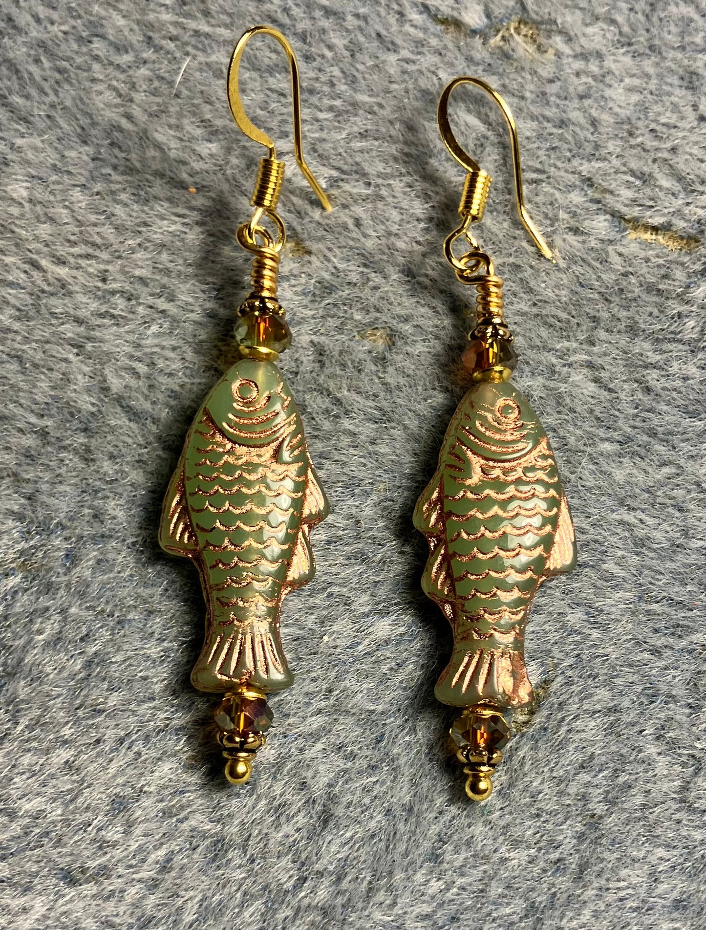 Olive green (with copper inlay) Czech glass fish bead earrings adorned with sparkly green Chinese crystal beads.