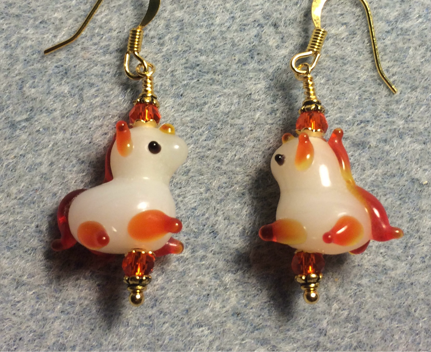 Small white and orange lamp work unicorn bead earrings adorned with orange Chinese crystal beads.