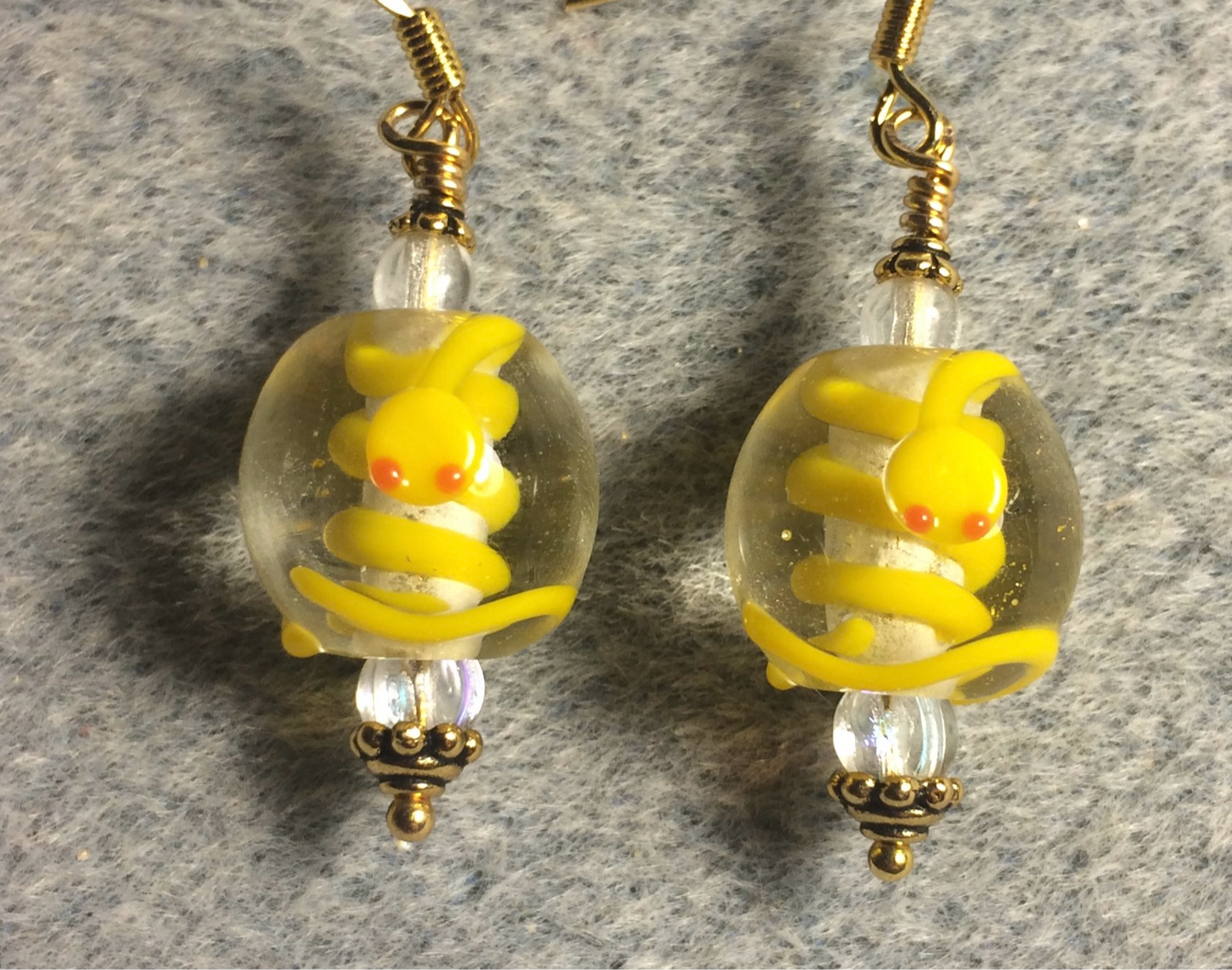 Clear and yellow lamp work snake bead earrings adorned with clear Czech glass beads.