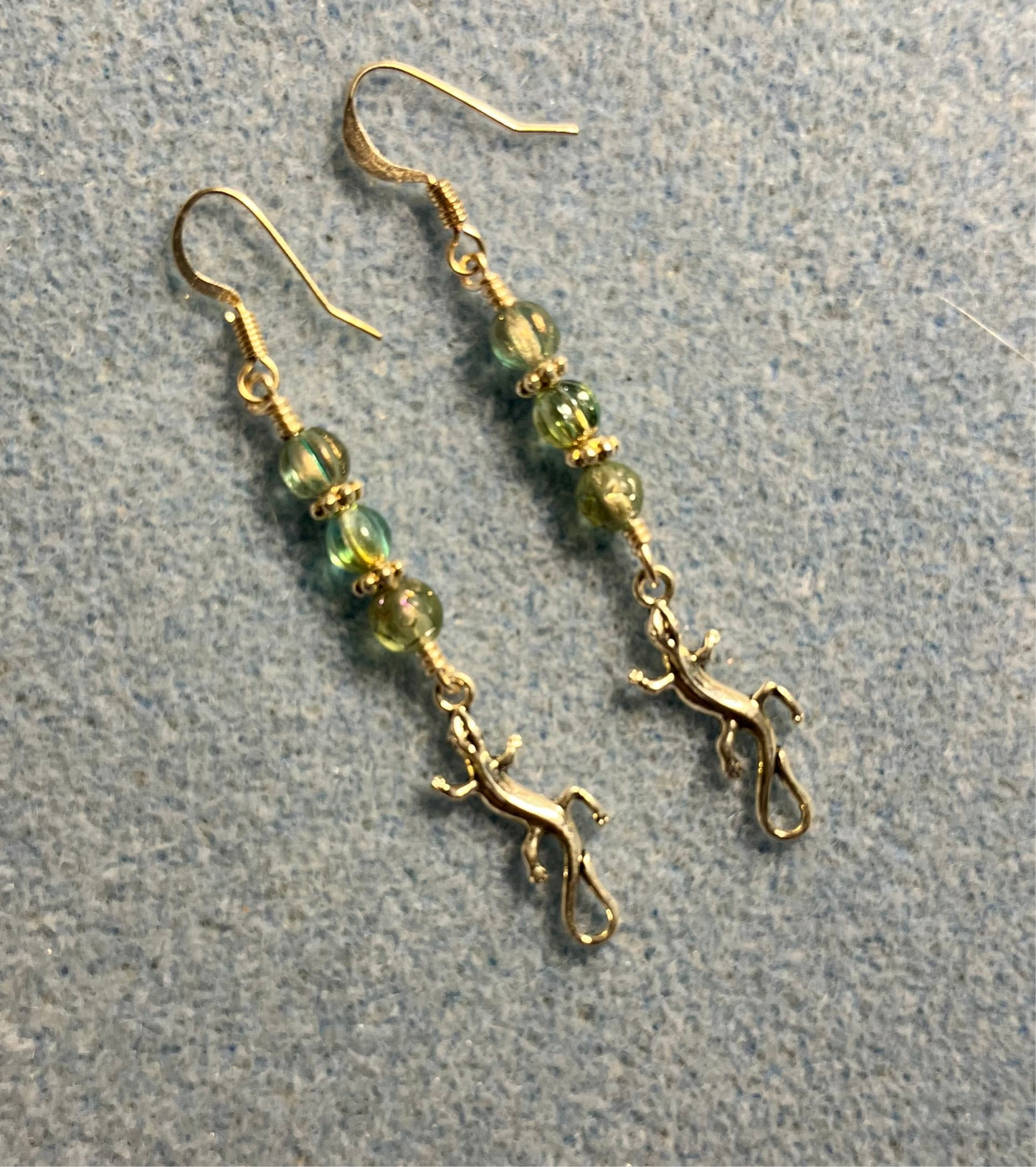 Tiny silver swirly tailed lizard charm earrings adorned with small green Czech glass beads