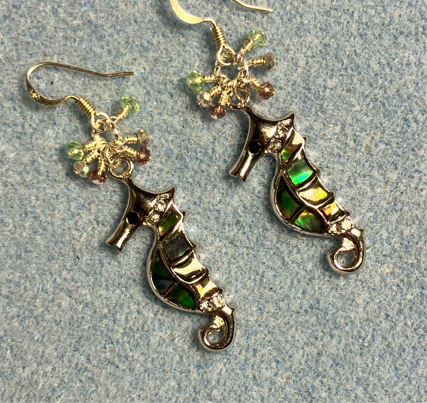 Silver and abalone seahorse charm earrings adorned with small dangling light green, silver, and violet Chinese crystal beads.