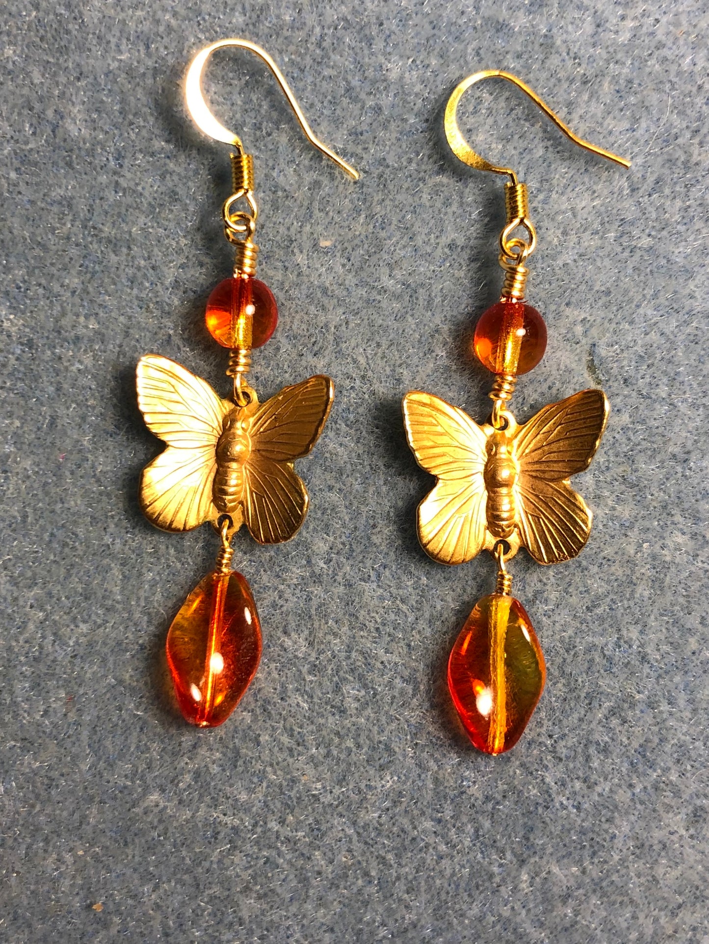 Gold butterfly charm connector earrings adorned with yellow orange Czech glass twist beads and yellow orange Czech glass beads.