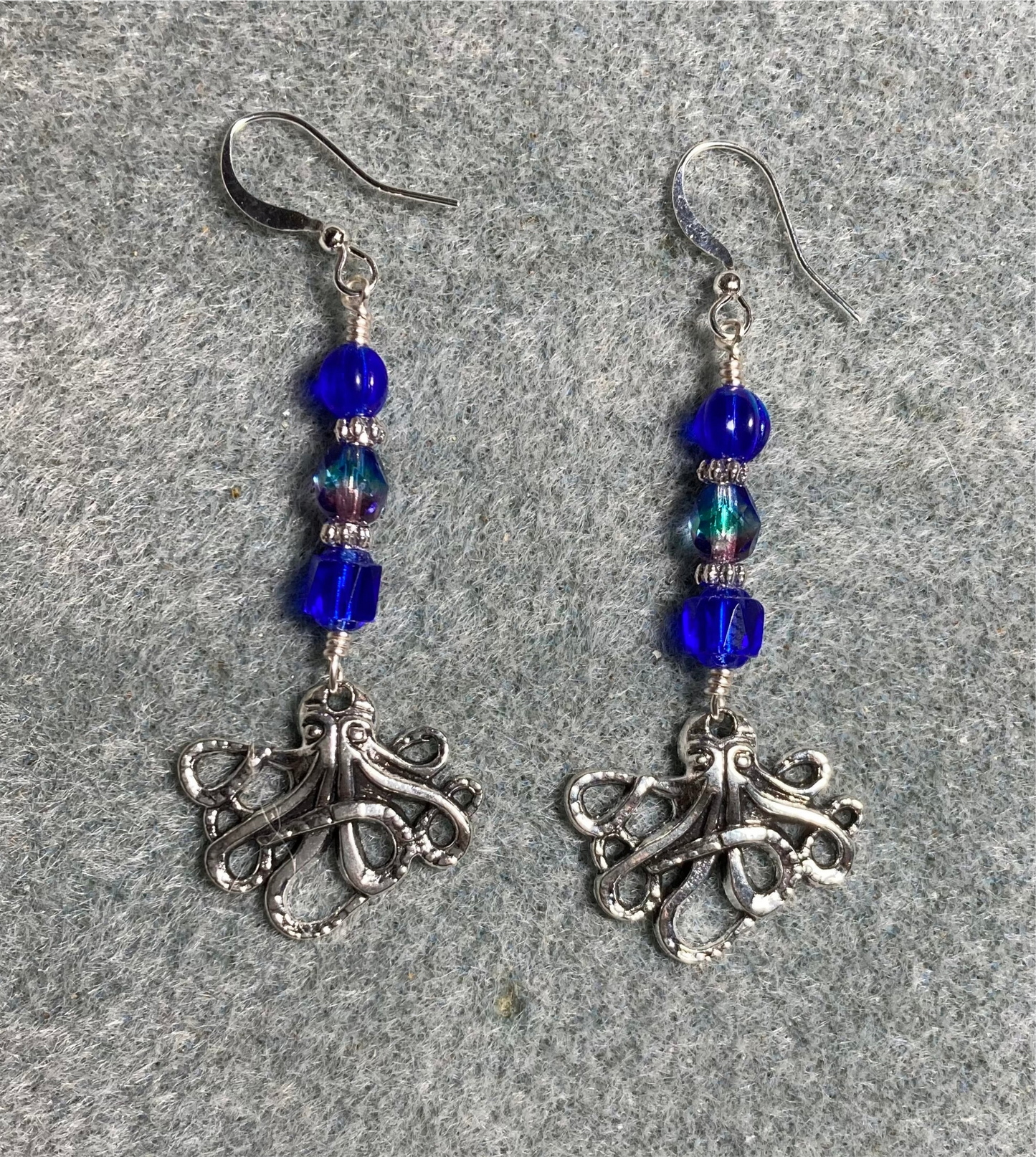 Silver octopus charm earrings adorned with dark blue Czech glass beads.
