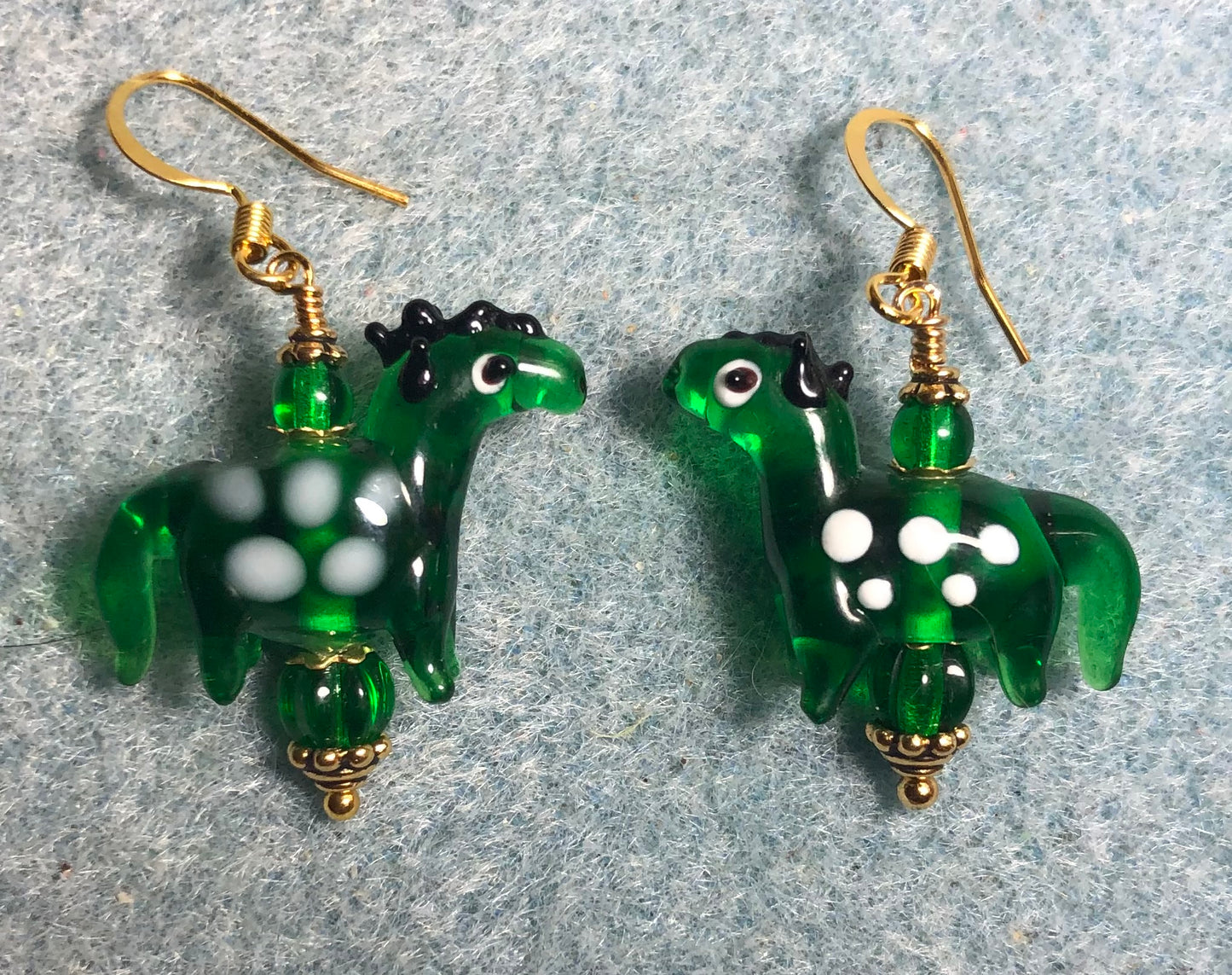 Translucent emerald green lamp work spotted horse bead earrings adorned with emerald green Czech glass beads.