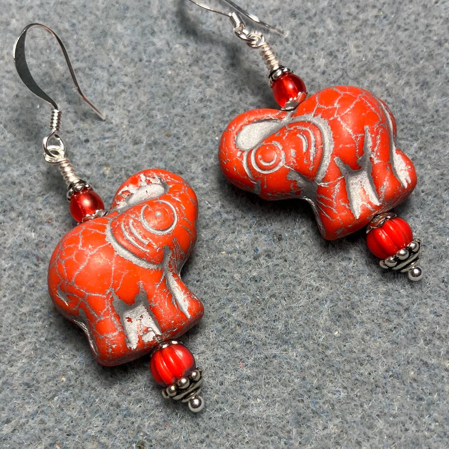 Orange red (with silver inlay) Czech glass elephant bead earrings adorned with light orange red Czech glass beads.