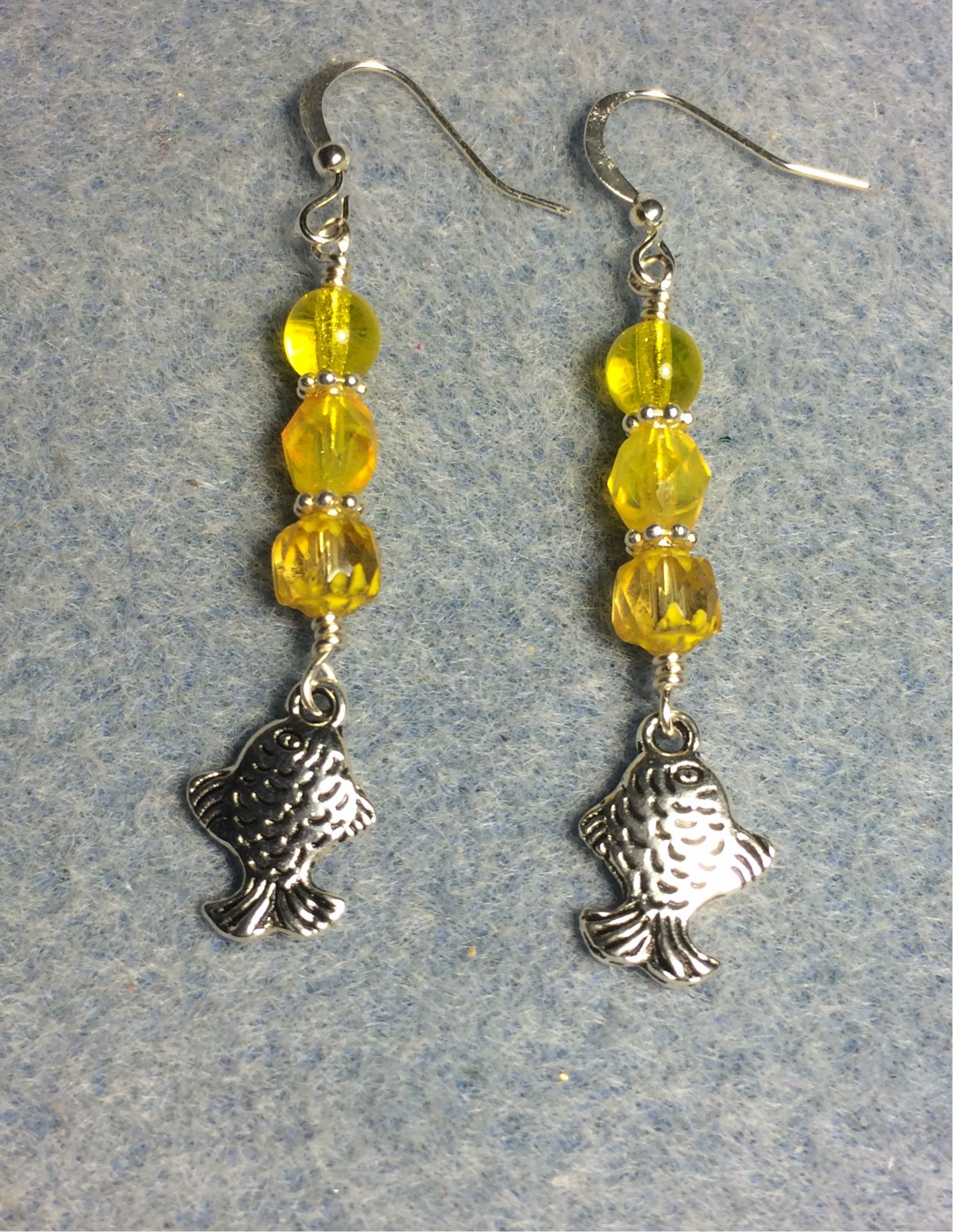 Silver fish charm earrings adorned with yellow Czech glass beads