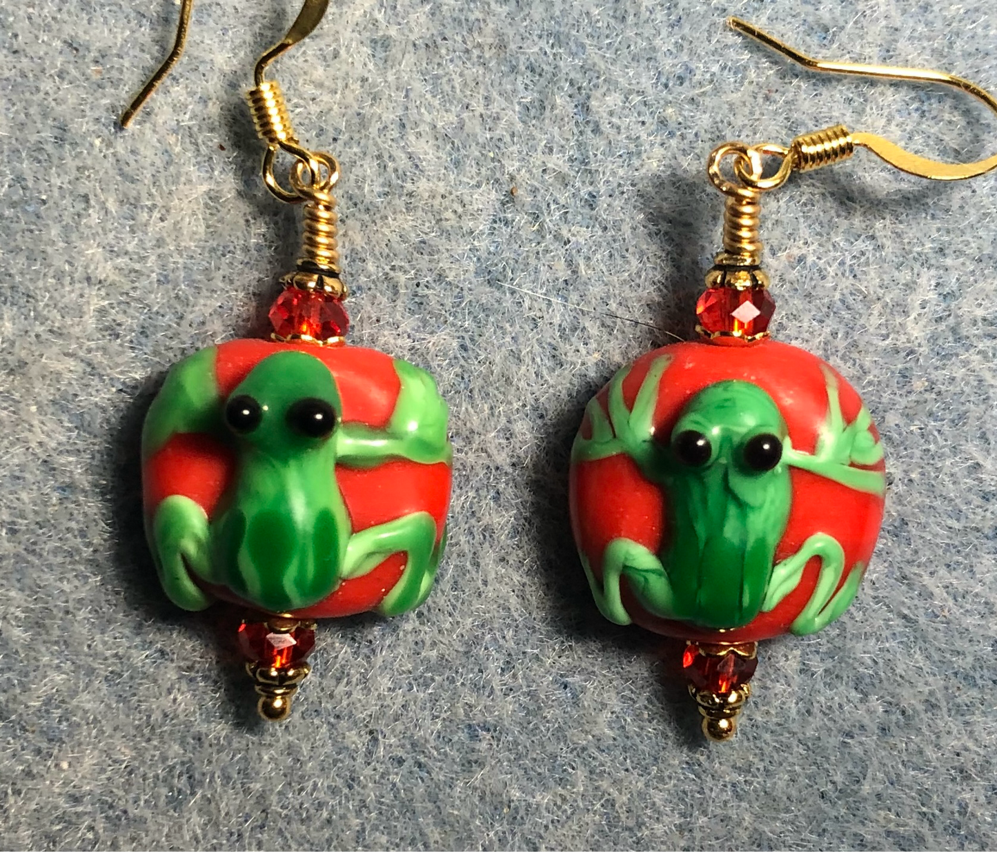 Red and green lamp work frog bead earrings adorned with red Chinese crystal beads.