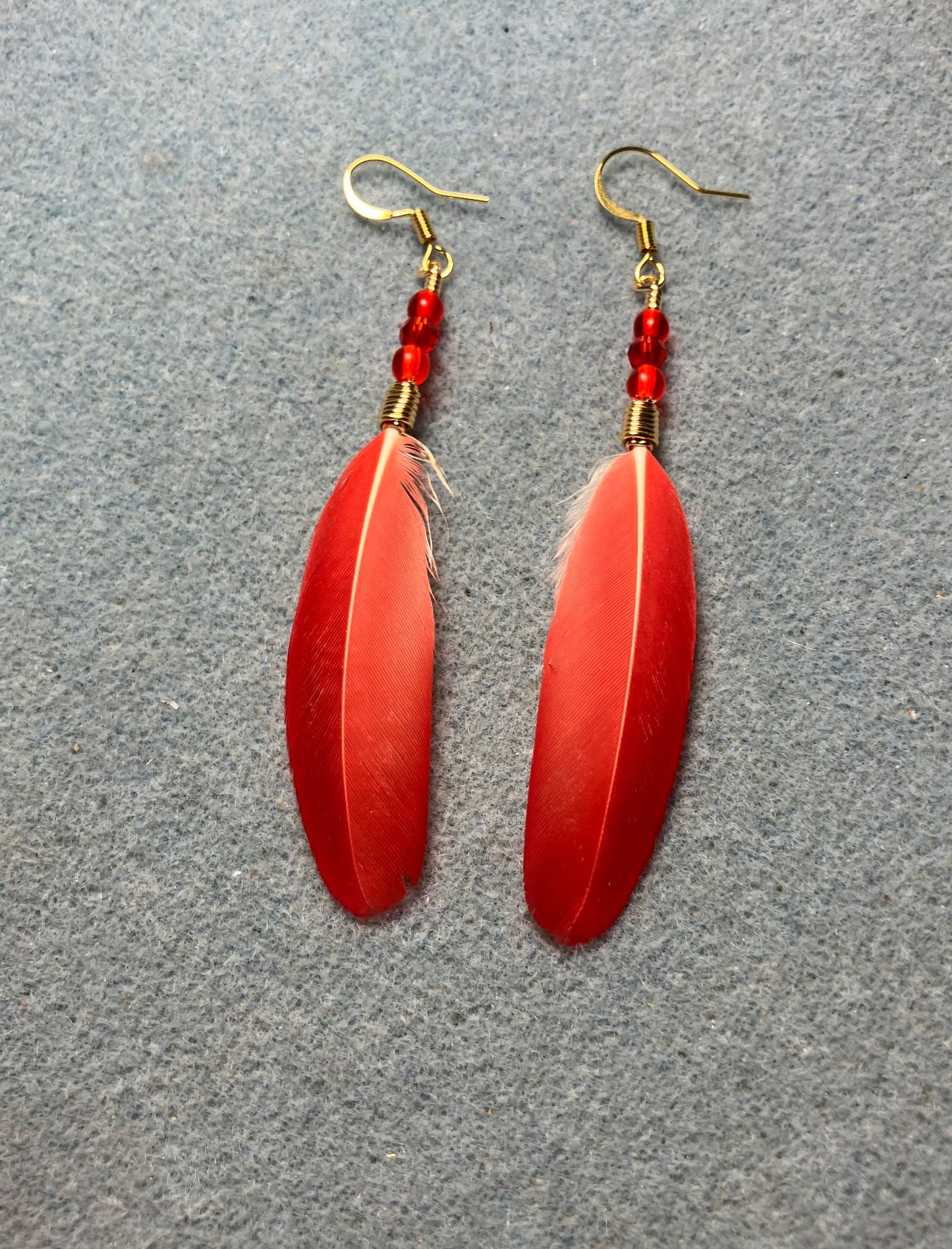 Bright red spectacled Amazon feather earrings adorned with small red Czech glass beads.