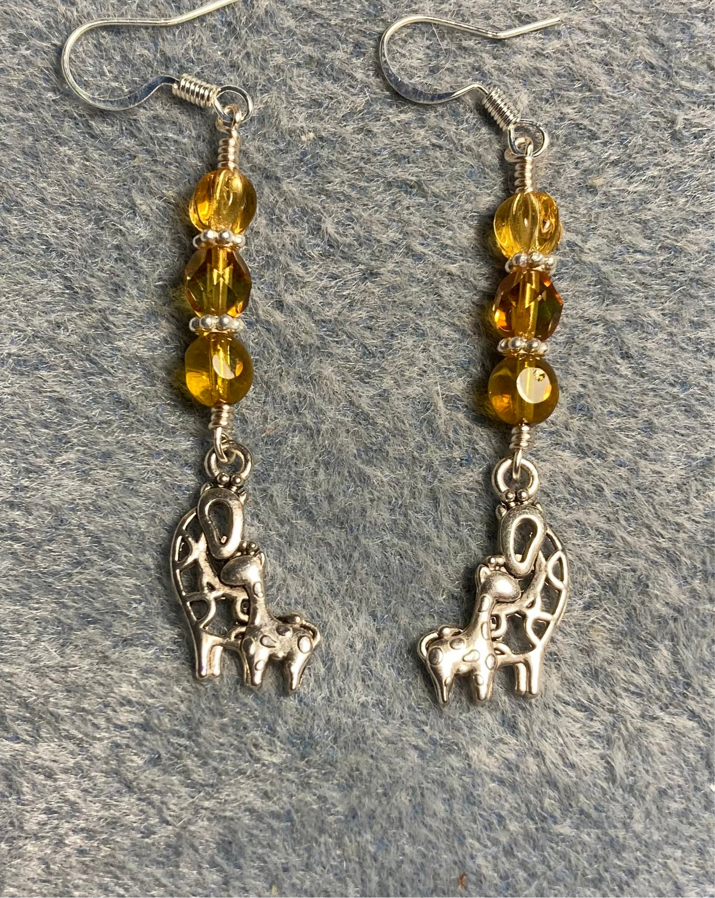 Silver mother and baby giraffe charm earrings adorned with amber Czech glass beads.