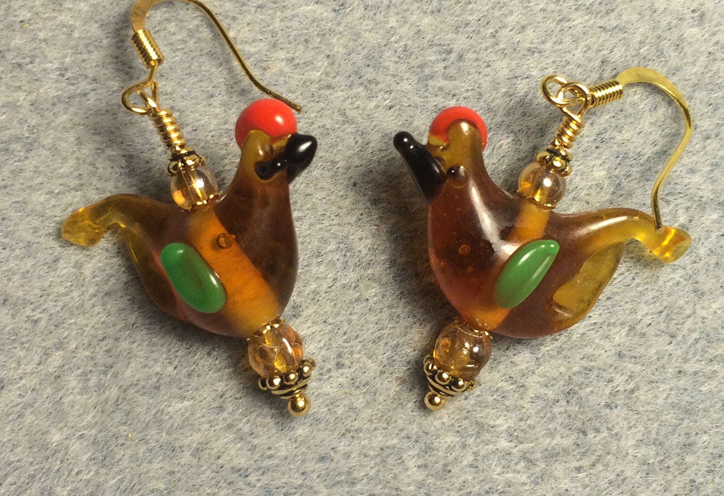 Translucent amber and green lamp work songbird bead earrings adorned with amber Czech glass beads.