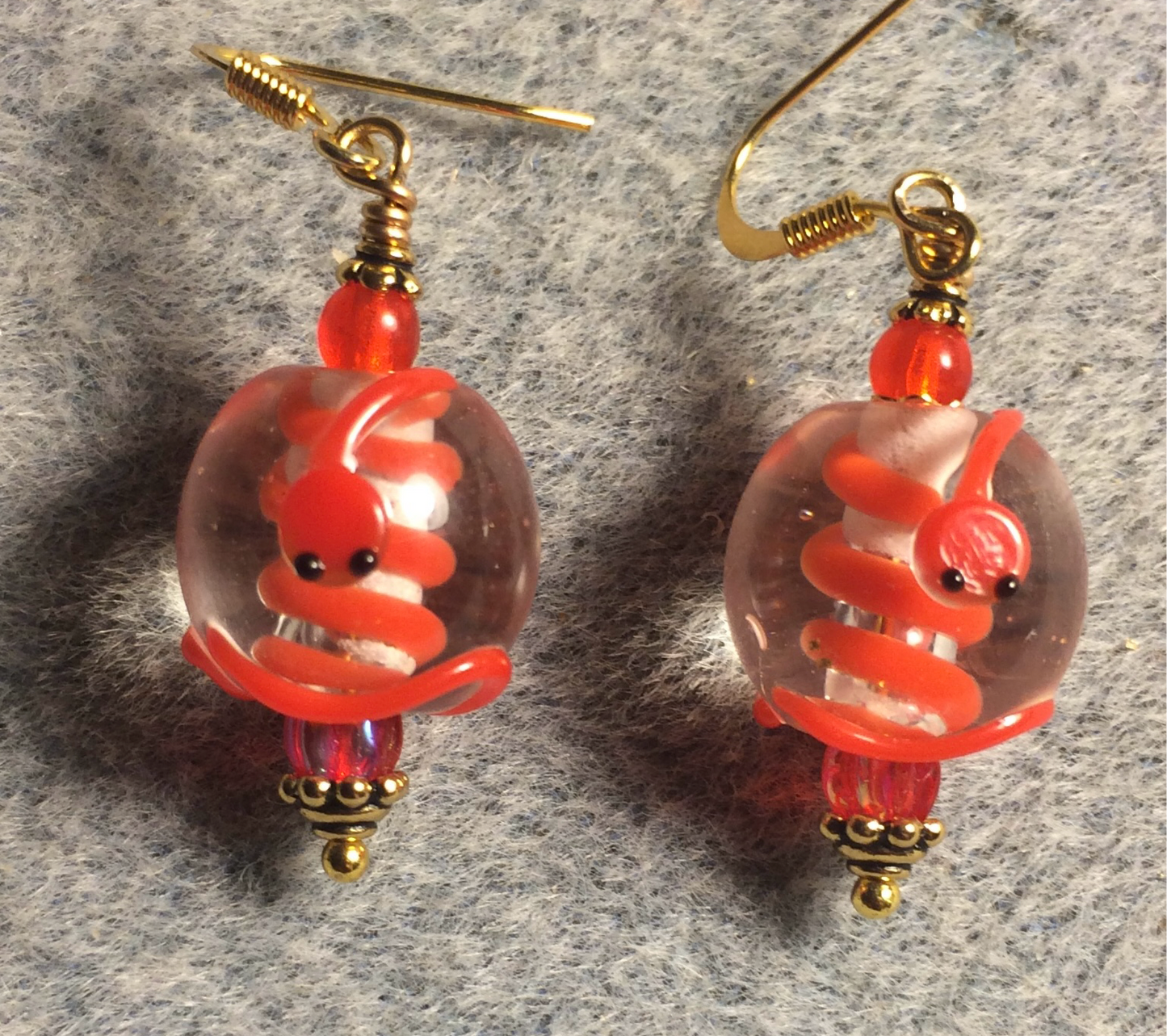 Clear and red lamp work snake bead earrings adorned with red Czech glass beads.