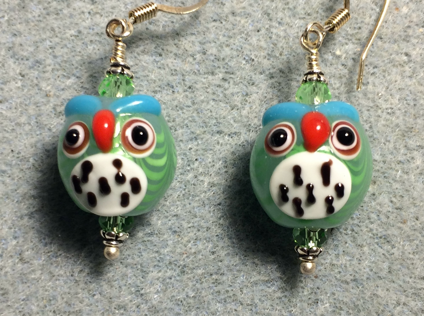 Light green and white lamp work spotted owl bead earrings adorned with light green Chinese crystal beads.