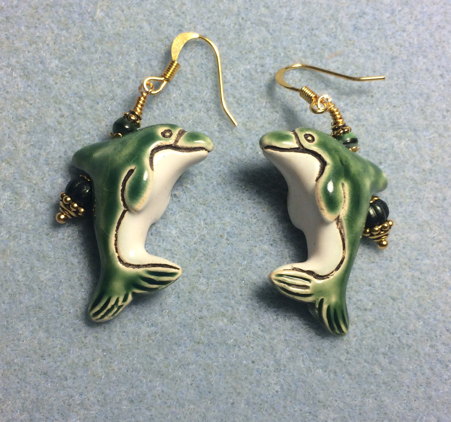 Green and white ceramic dolphin bead earrings adorned with green Czech glass beads.