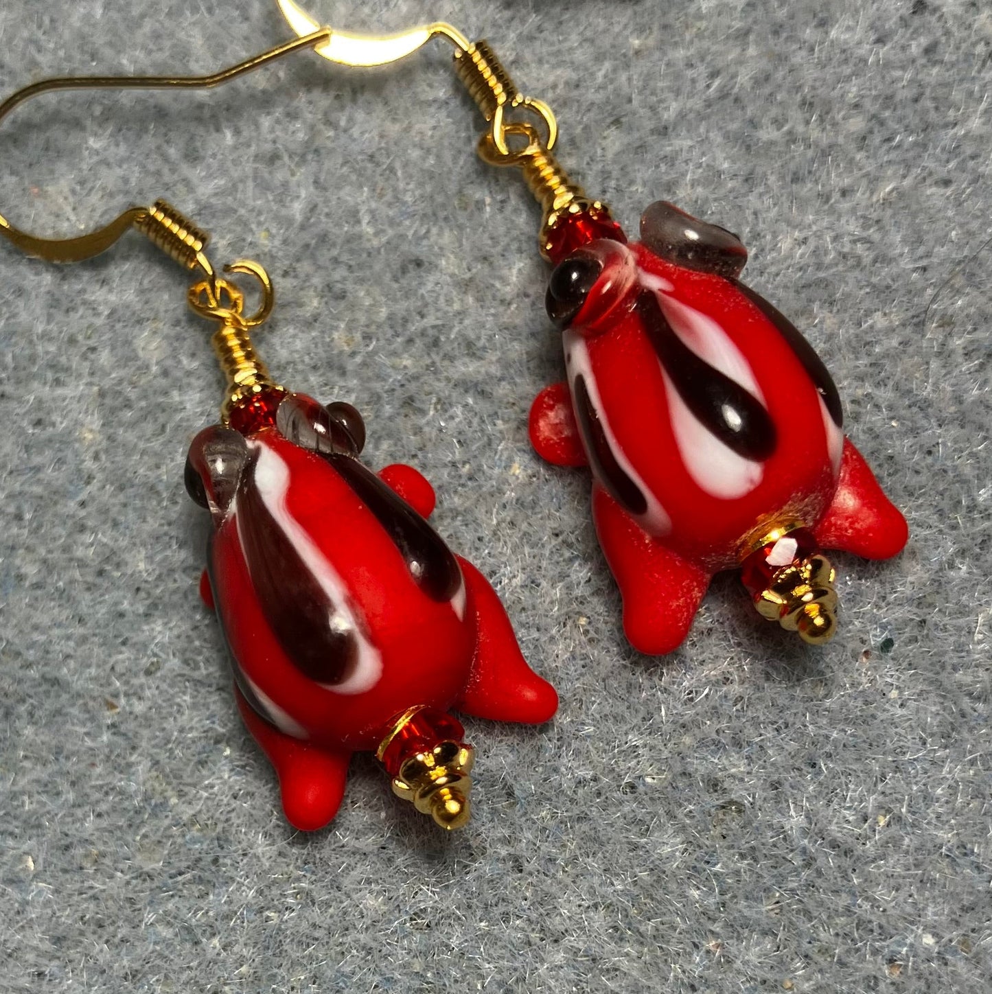 Very small red with black stripes lamp work frog bead earrings adorned with red Chinese crystal beads.