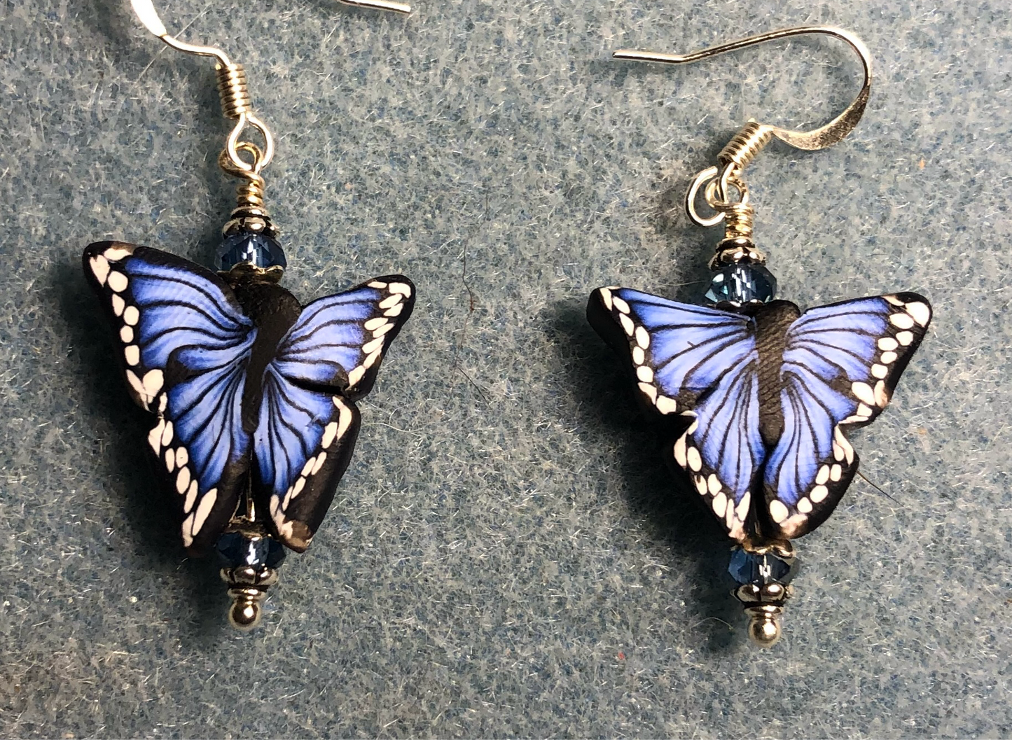 Blue and black polymer clay butterfly bead earrings adorned with blue Chinese crystal beads.