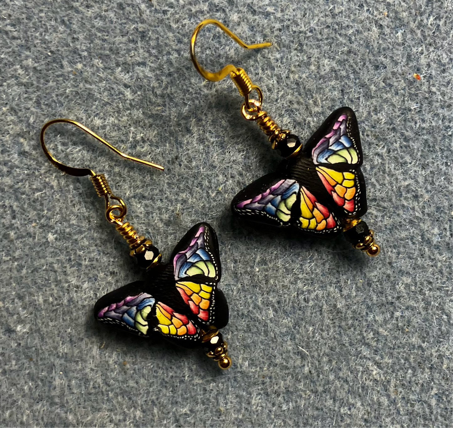 Multicolored polymer clay butterfly bead earrings adorned with black Chinese crystal beads.