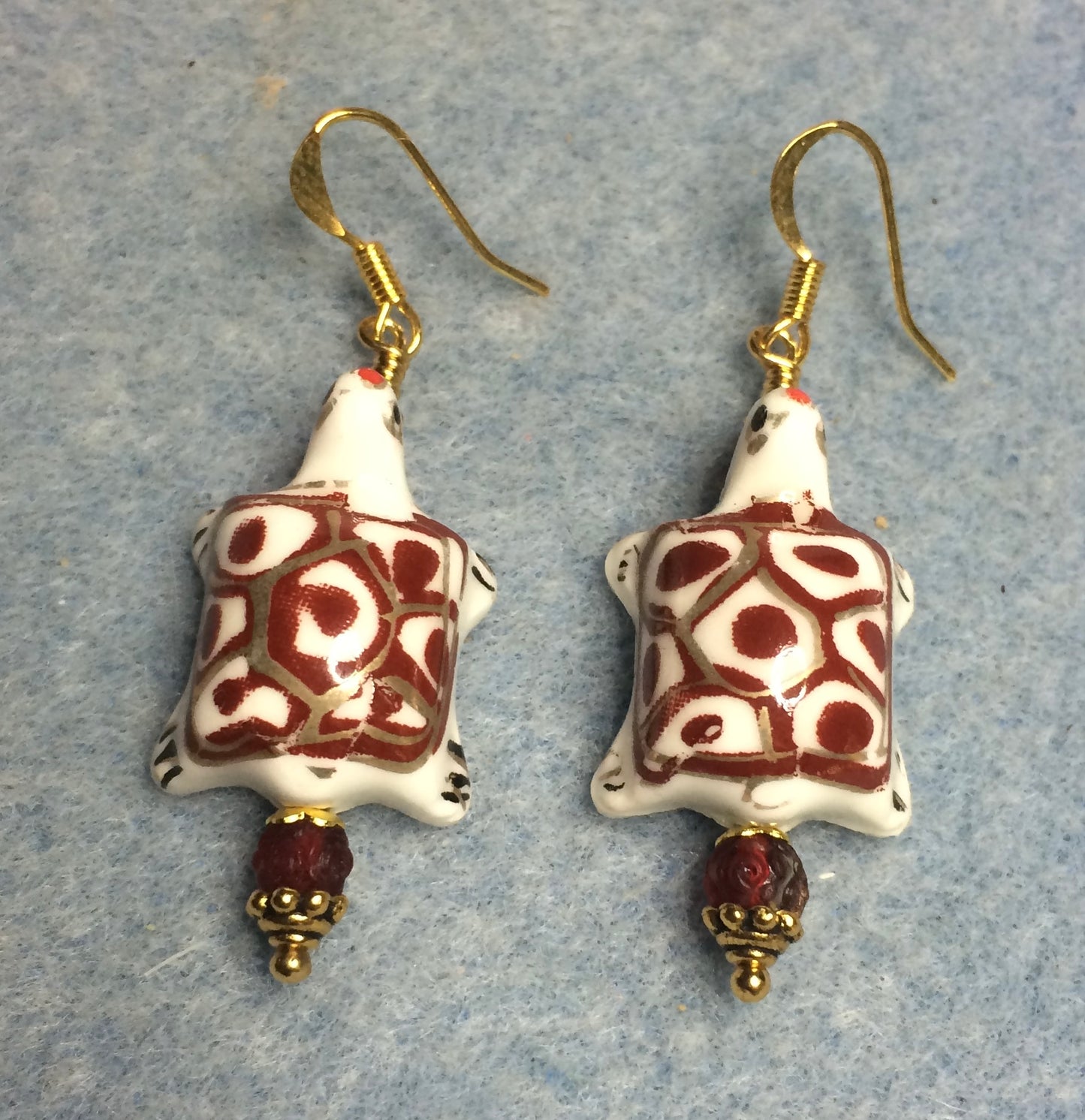 Dark red and white ceramic spotted turtle bead earrings adorned with dark red Czech glass beads.
