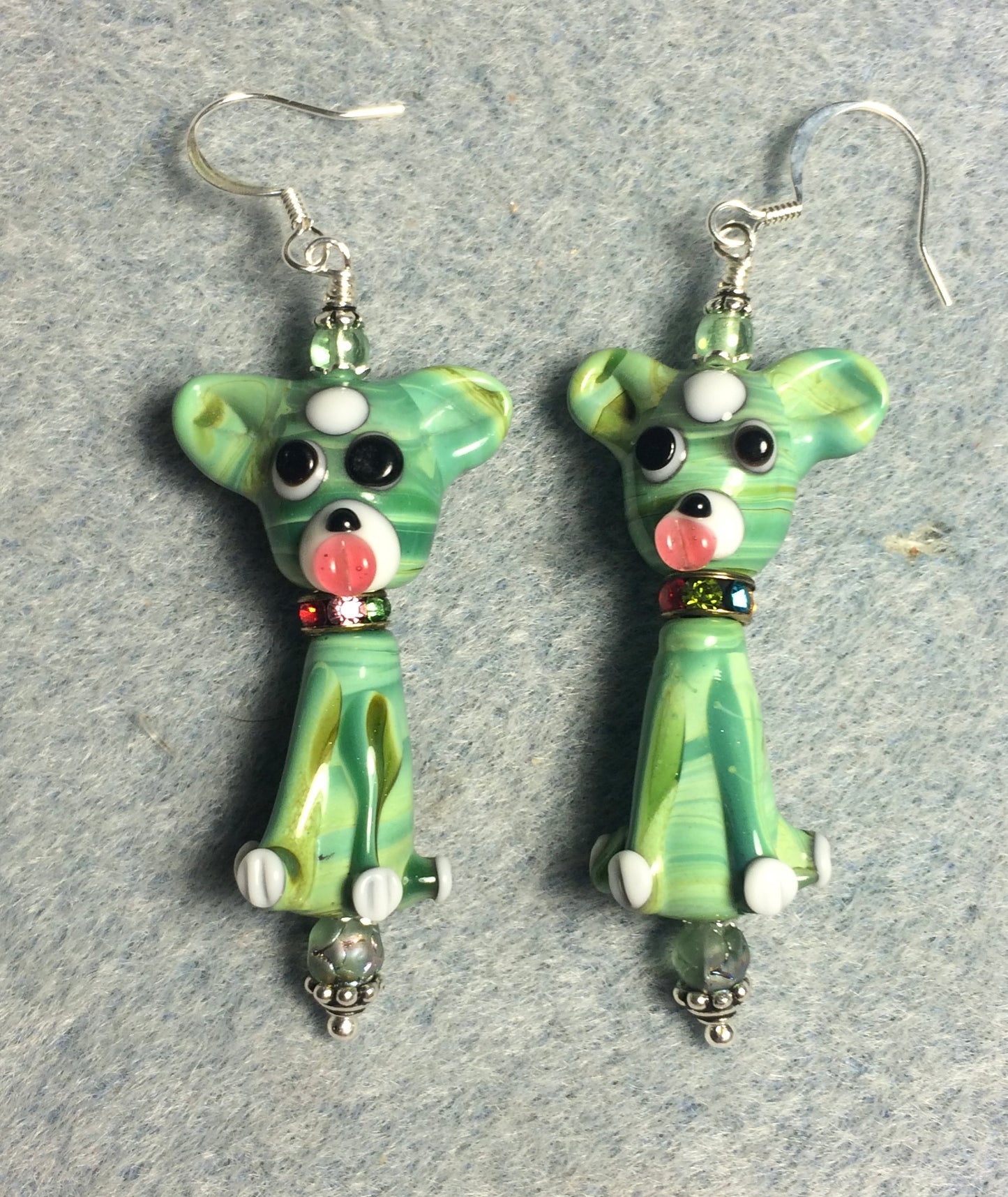 Green and white lamp work dog bead earrings adorned with colorful rhinestone rondelle “collars” and green Czech glass beads.