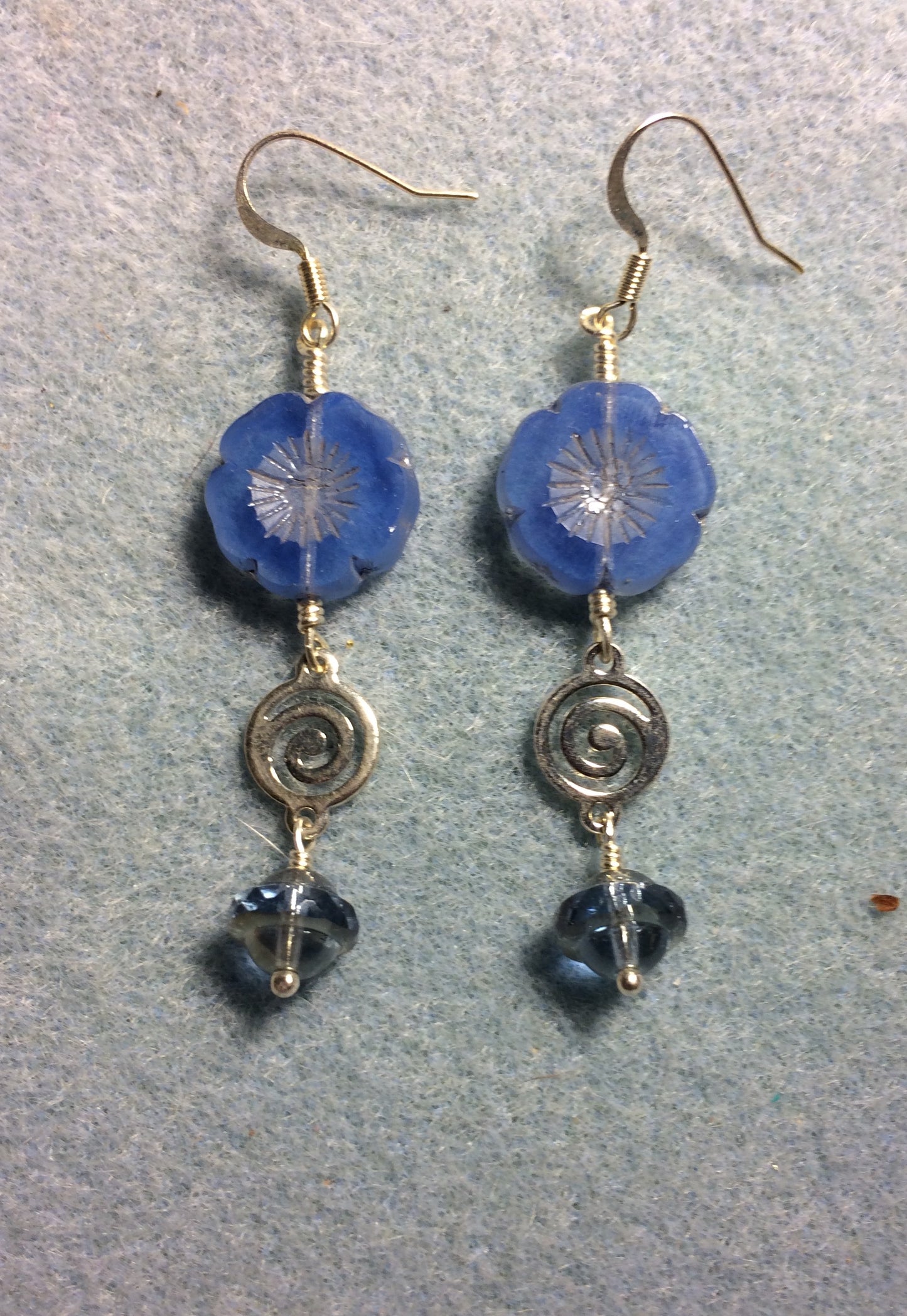 Light blue Czech glass pansy bead earrings adorned with silver swirly connectors and light blue Czech glass Saturn beads.