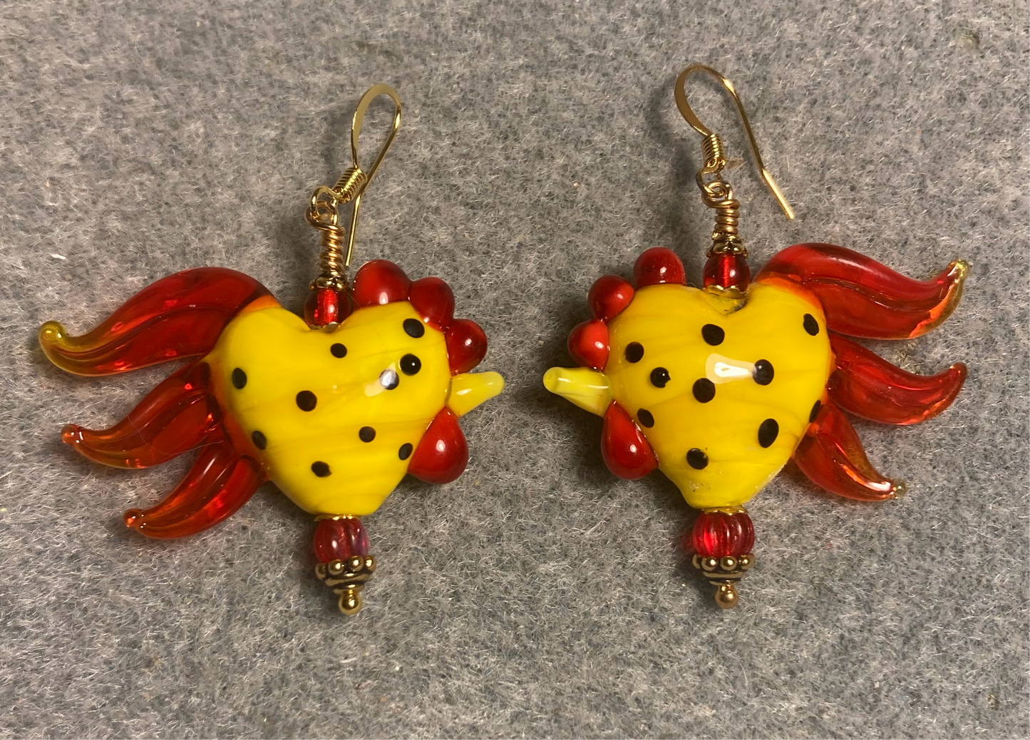 Yellow and red with black spots heart shaped lamp work rooster bead earrings adorned with red Czech glass beads.