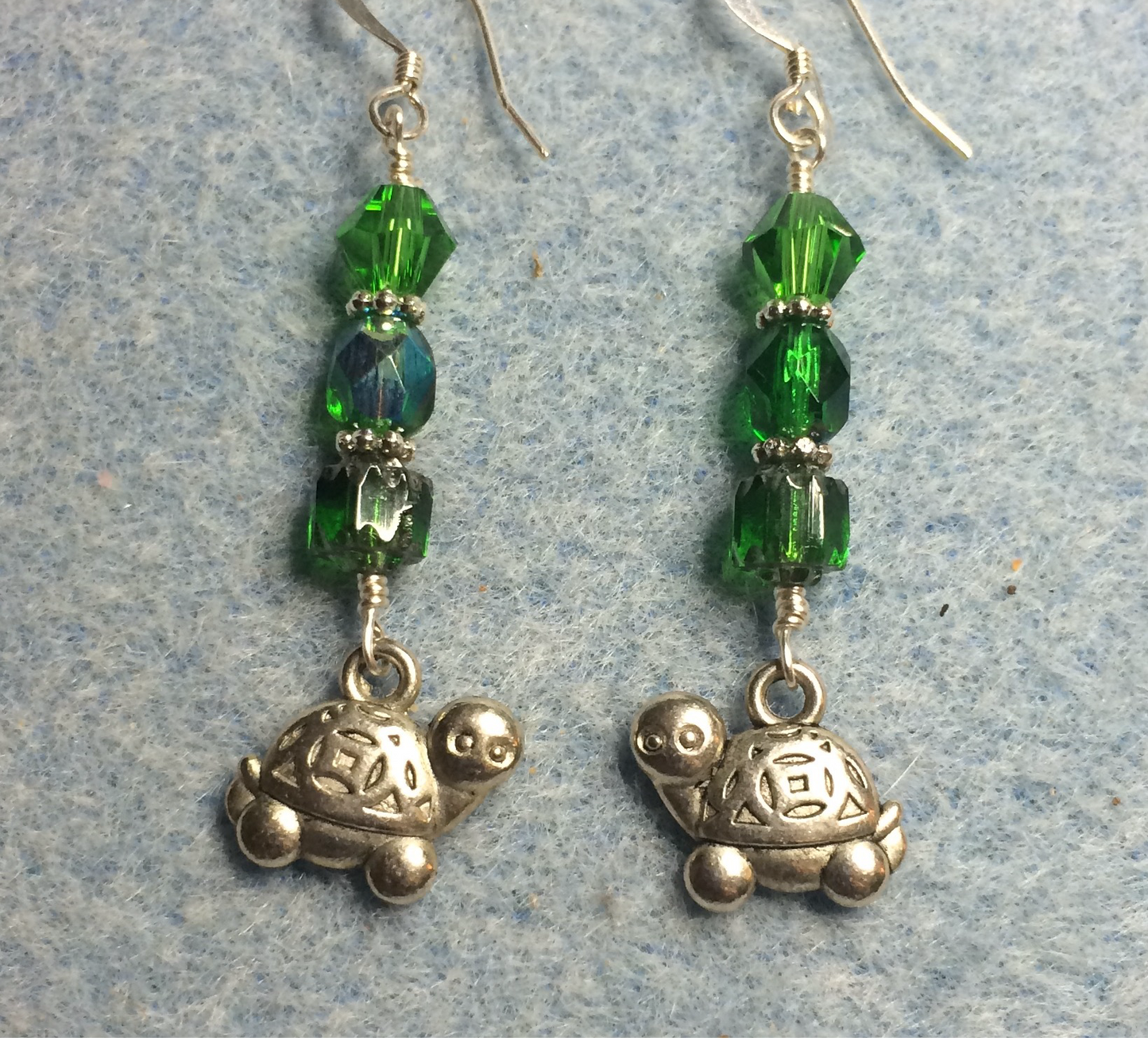 Silver turtle charm earrings adorned with emerald green Czech glass beads.