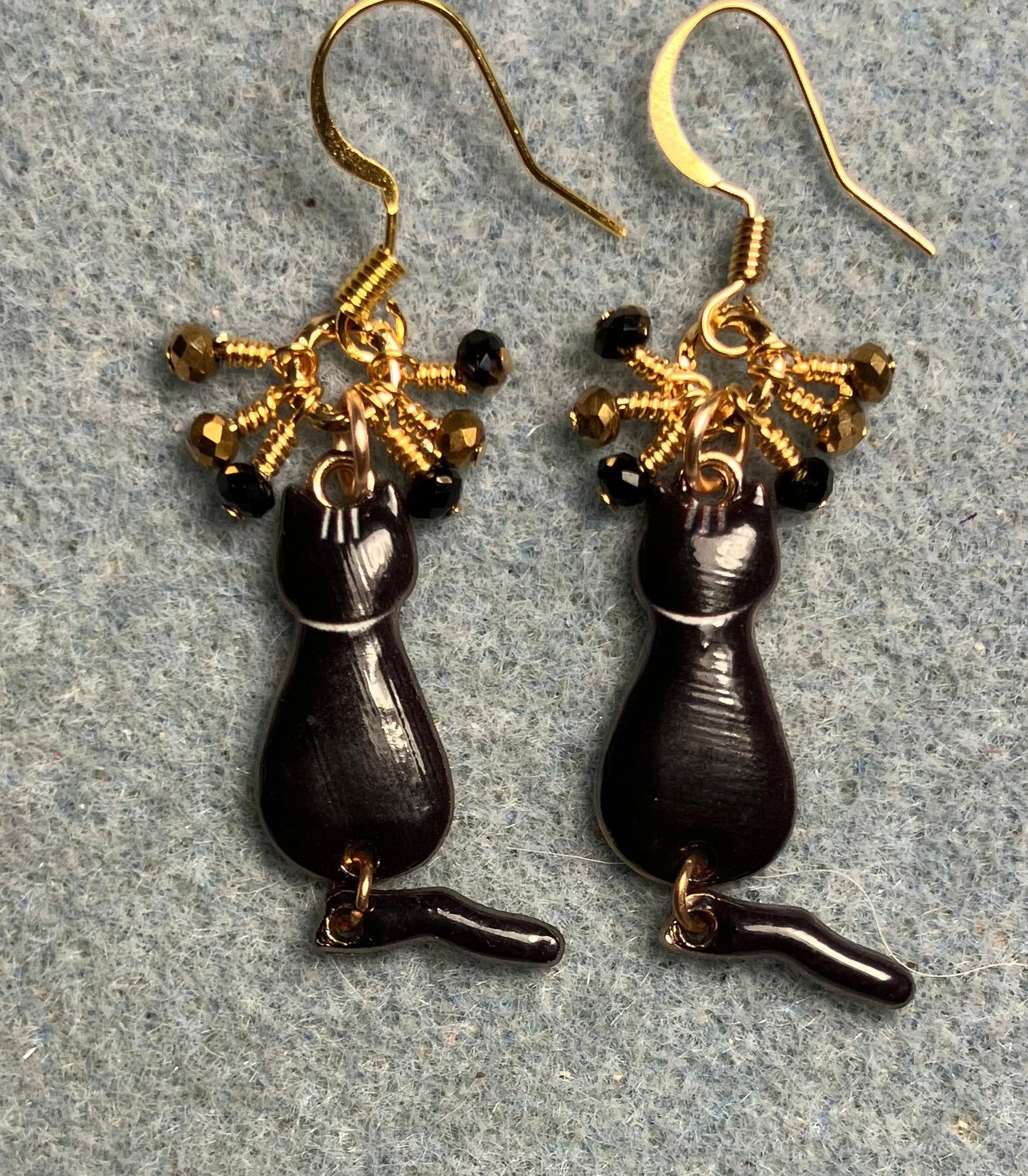 Black and gold enamel cat charm earrings adorned with tiny dangling black and gold Chinese crystal beads.