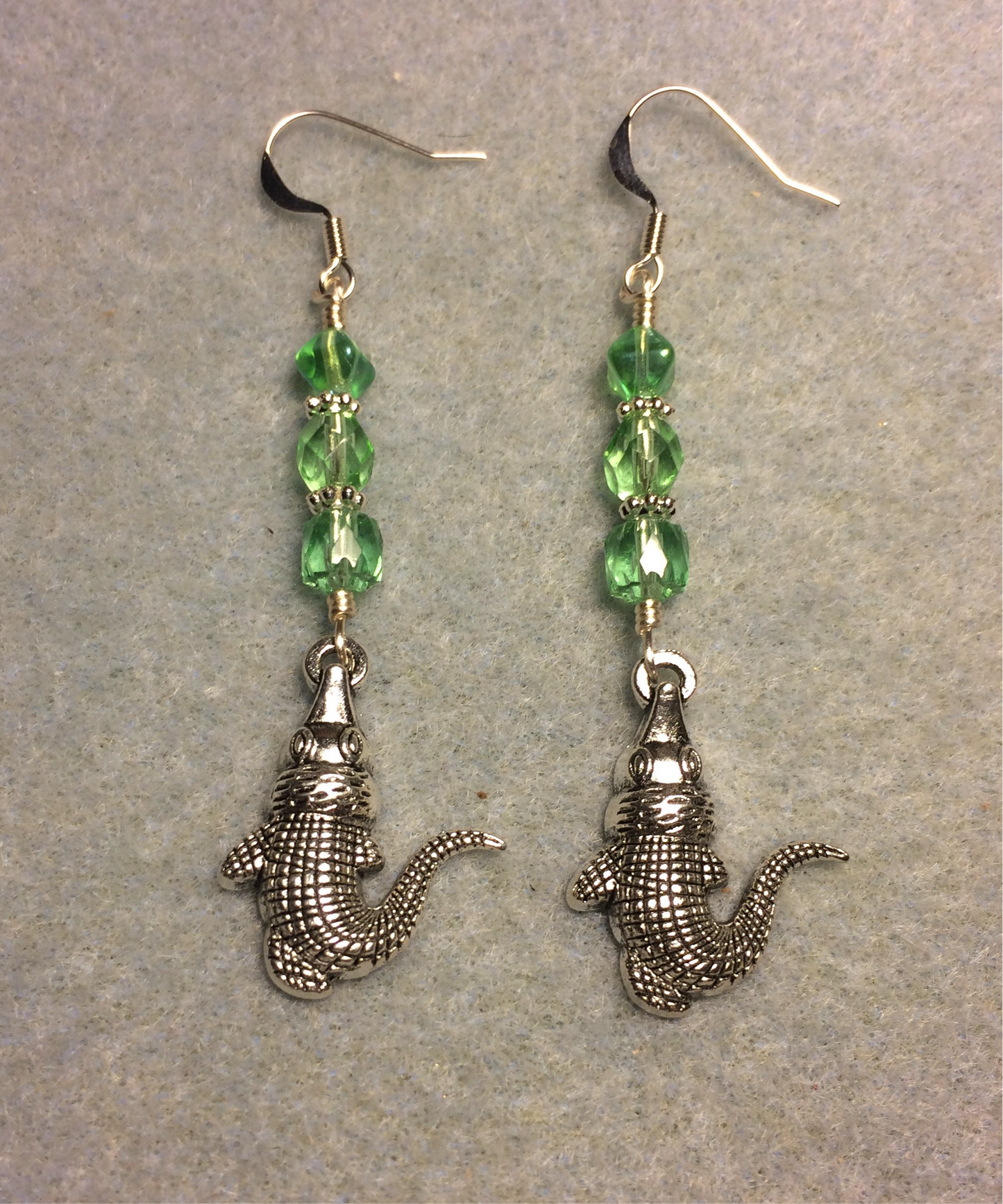 Silver alligator charm earrings adorned with light green Czech glass beads
