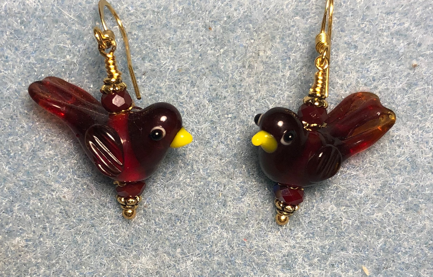Translucent dark red lamp work songbird bead earrings adorned with dark red Chinese crystal beads.