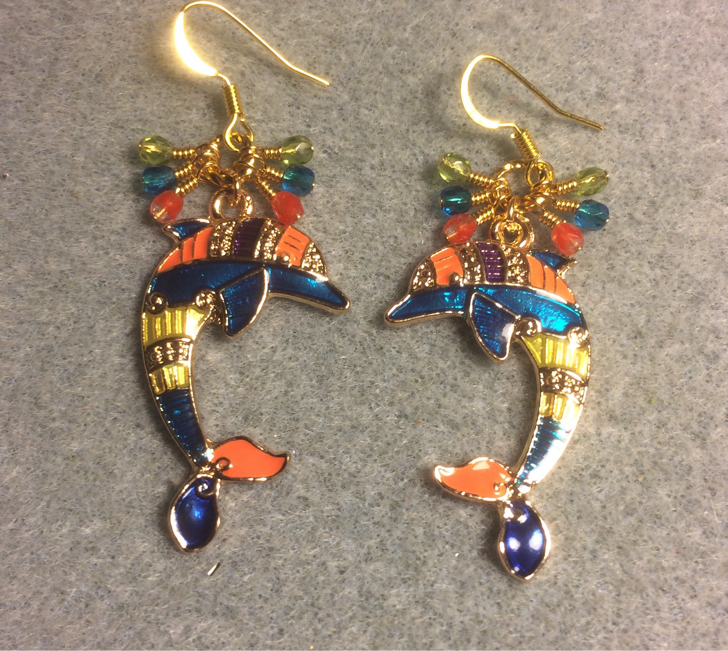 Large turquoise, olive green, and orange enamel dolphin charm earrings adorned with small dangling turquoise, olive green, and orange Czech glass beads.