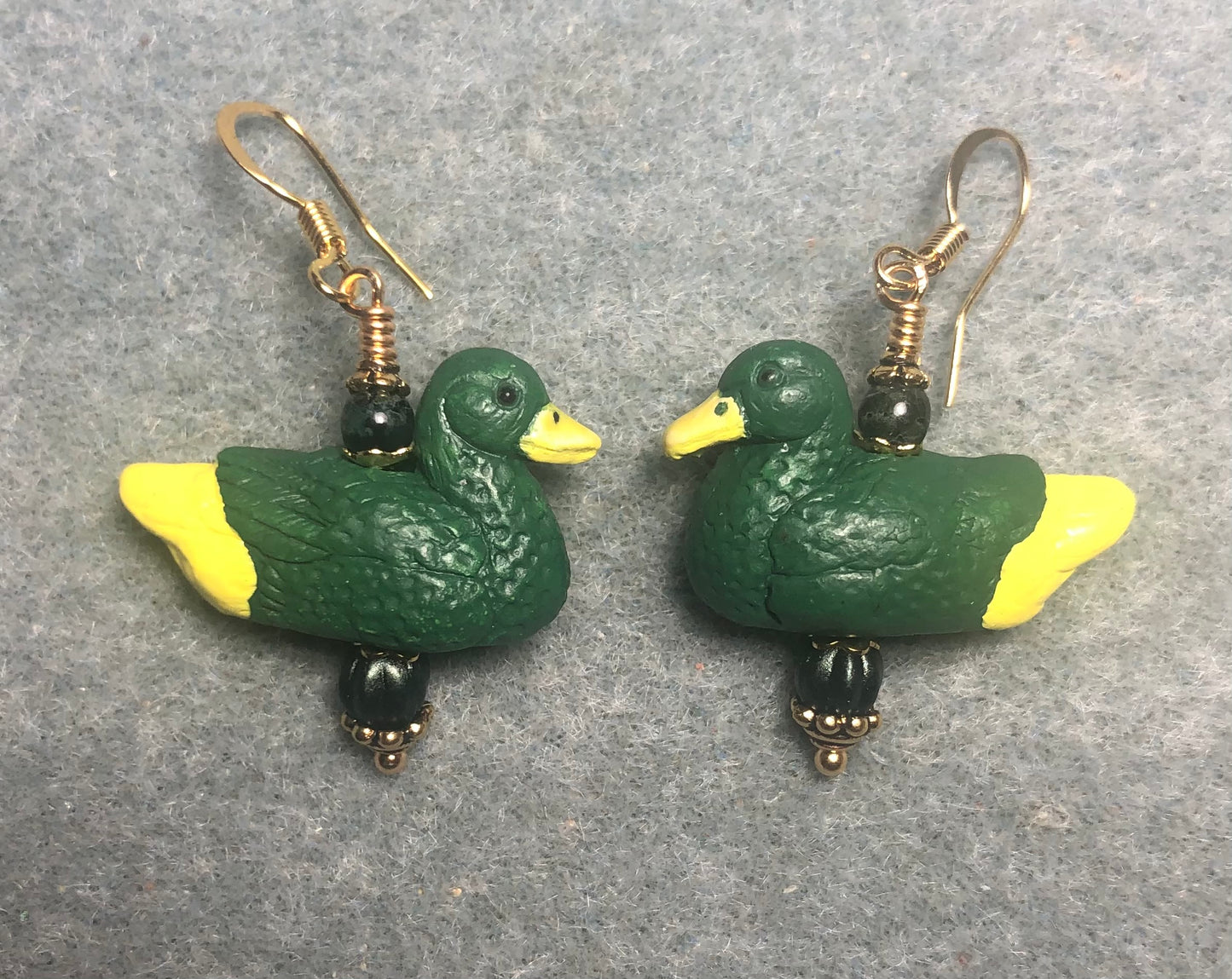 Dark green and yellow ceramic duck bead earrings adorned with dark green Czech glass beads.
