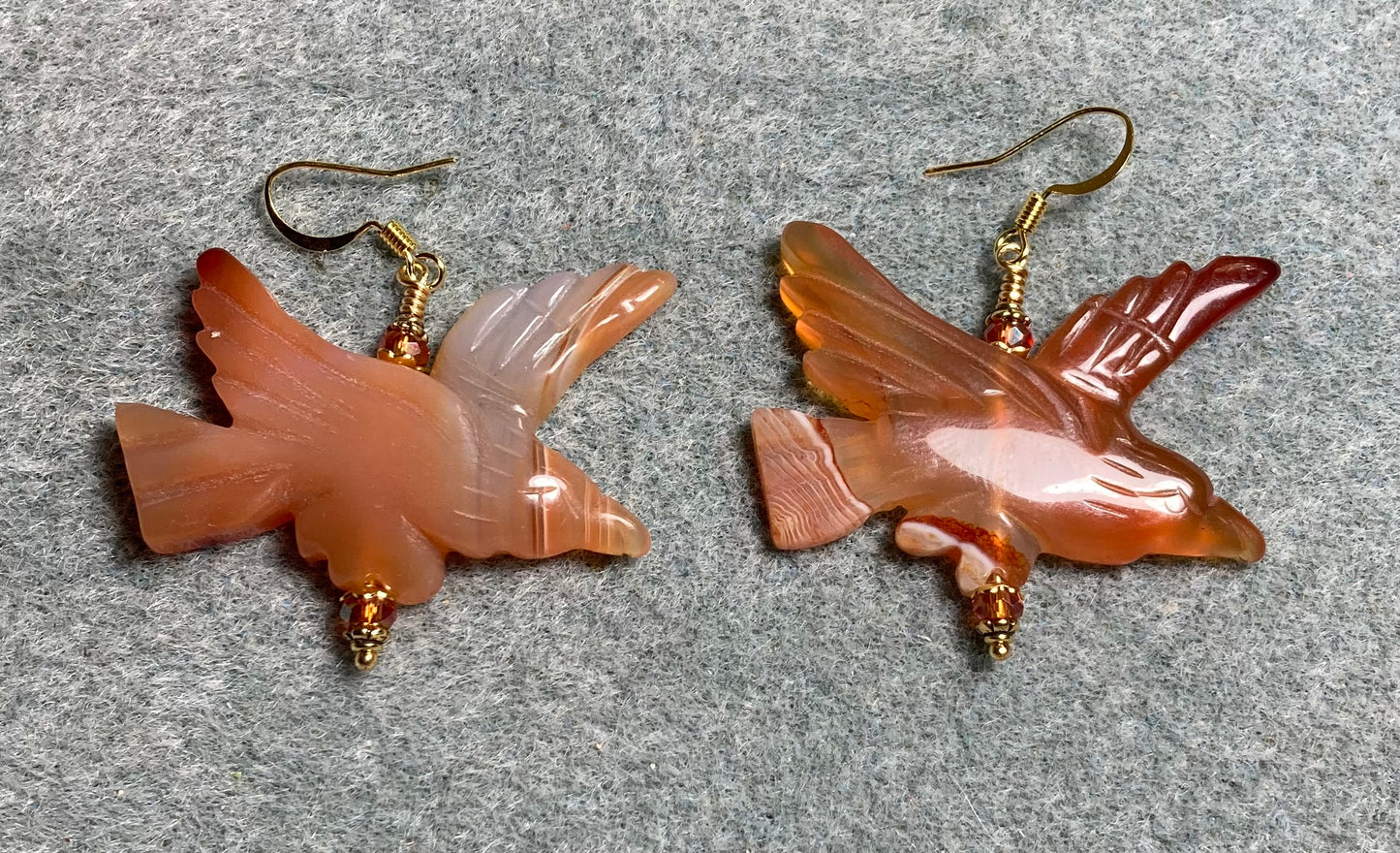 Large red orange carnelian gemstone flying eagle bead earrings adorned with orange Chinese crystal beads.