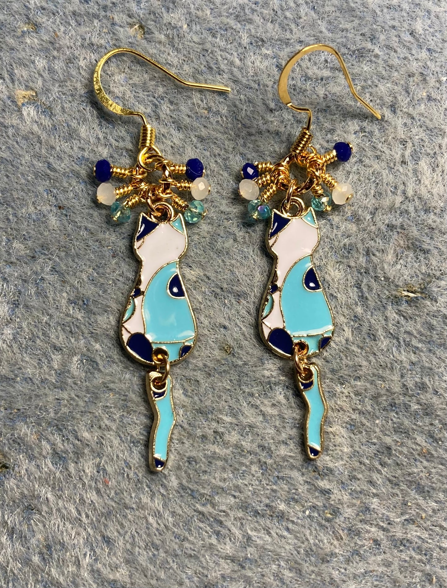 Turquoise, dark blue, and white enamel cat charm earrings adorned with tiny dangling turquoise, dark blue, and white Chinese crystal beads.