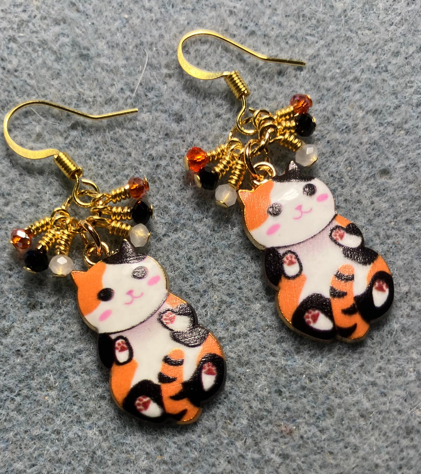 Orange, black, and white enamel calico cat charm earrings adorned with tiny dangling orange, black, and white Chinese crystal beads.