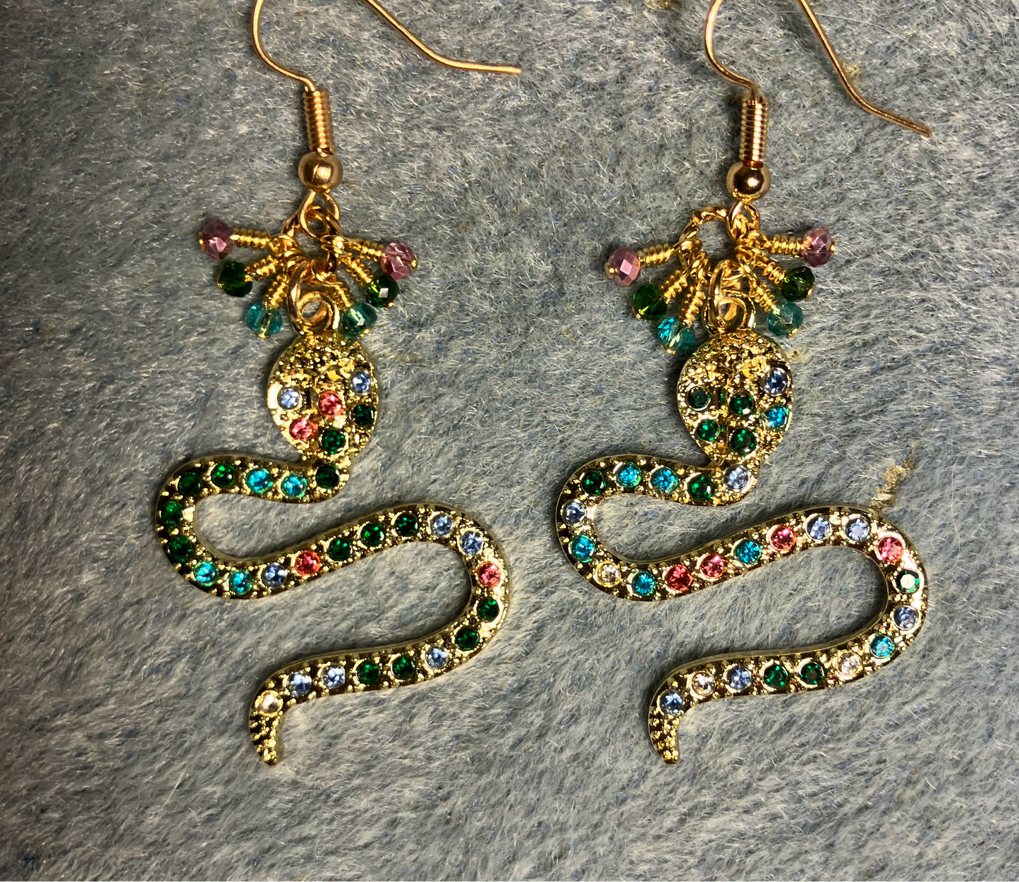 Gold and colored rhinestone coiled snake charm earrings adorned with tiny dangling aqua, pink, and dark green Chinese crystal beads.