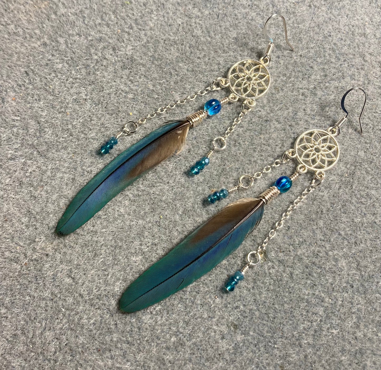 Aqua parrot feather earrings attached to silver chandelier findings and adorned with turquoise Czech glass melon beads and silver chain and tiny aqua Chinese crystal beads.