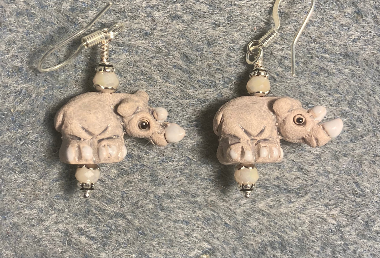 Small beige and white ceramic rhinoceros bead earrings adorned with white Chinese crystal beads.