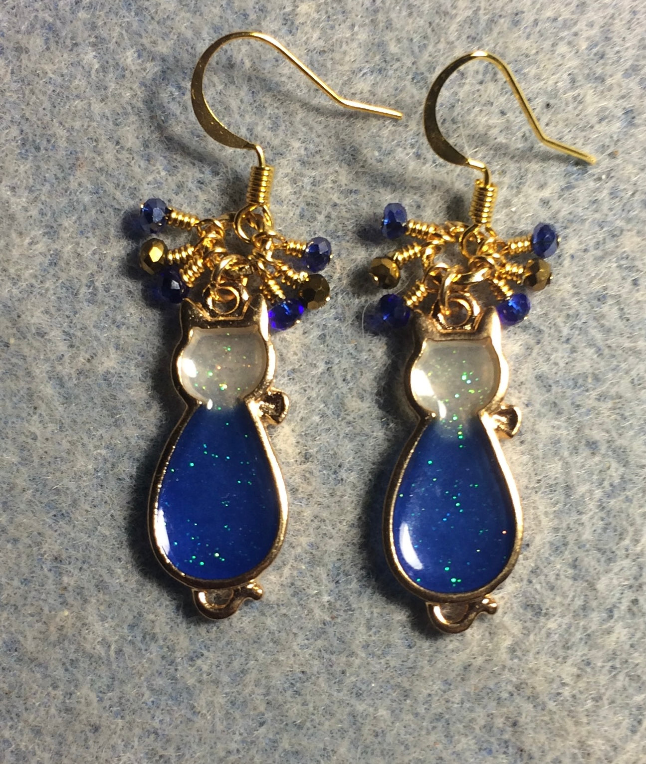 Blue and gold sparkly resin cat charm earrings adorned with small dangling blue and gold Chinese crystal beads.